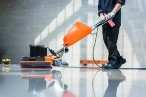 Person operating a floor cleaning machine in a large indoor space.