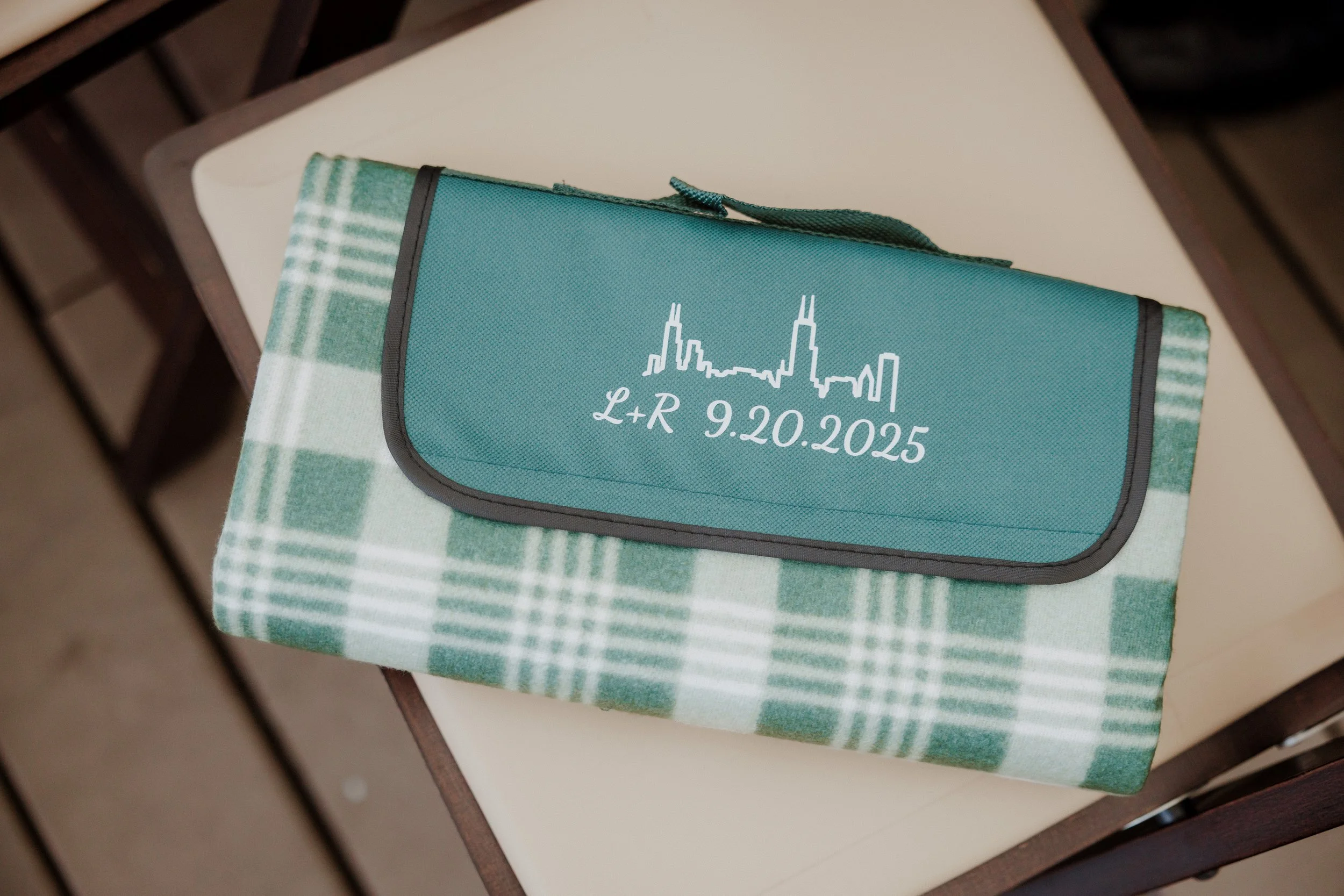 A teal future book bag with the skyline of Chicago and date 9.20.2025 on it, sitting on a checkered tablecloth.