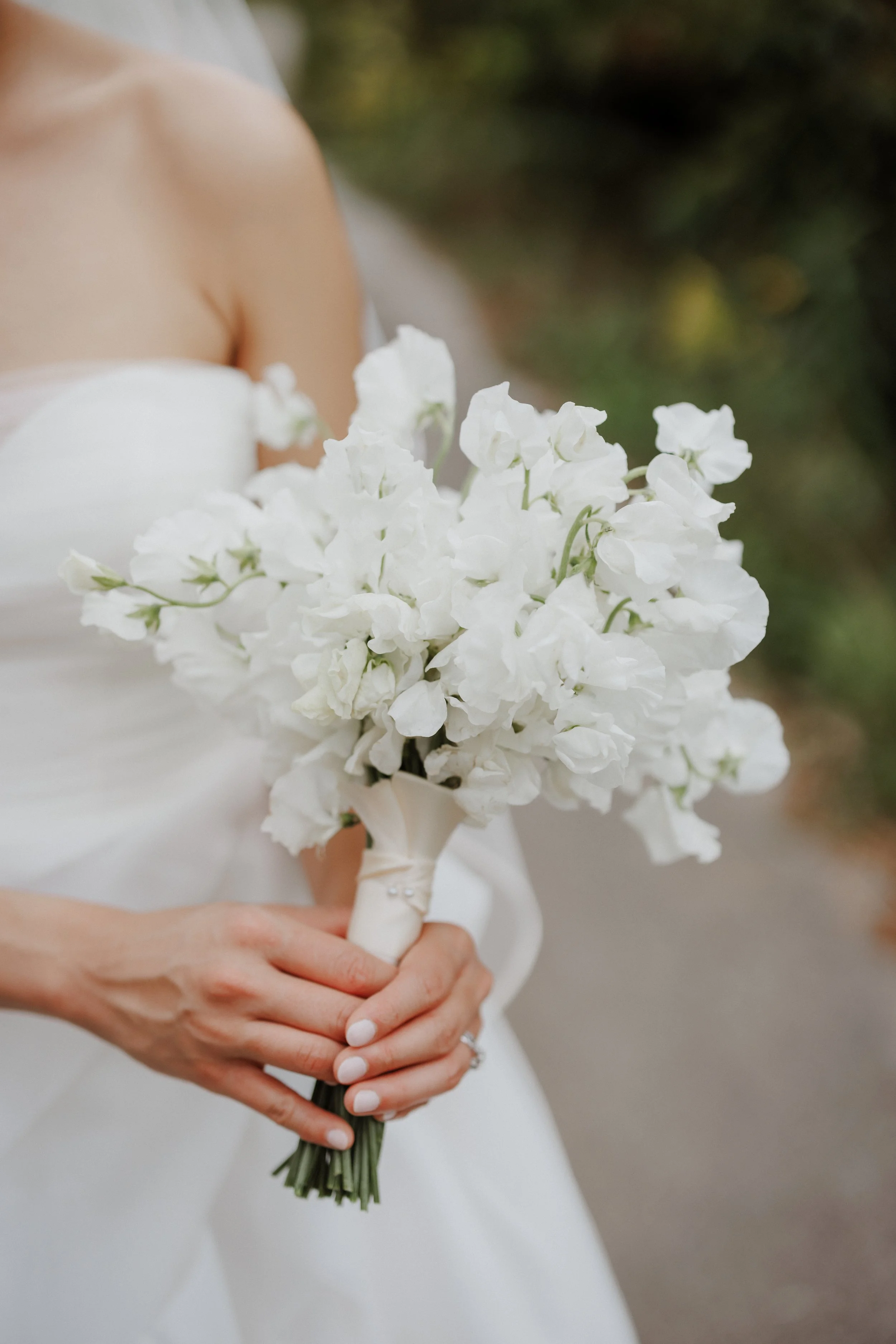 A bride in a white wedding dress holding a bouquet of white flowers.