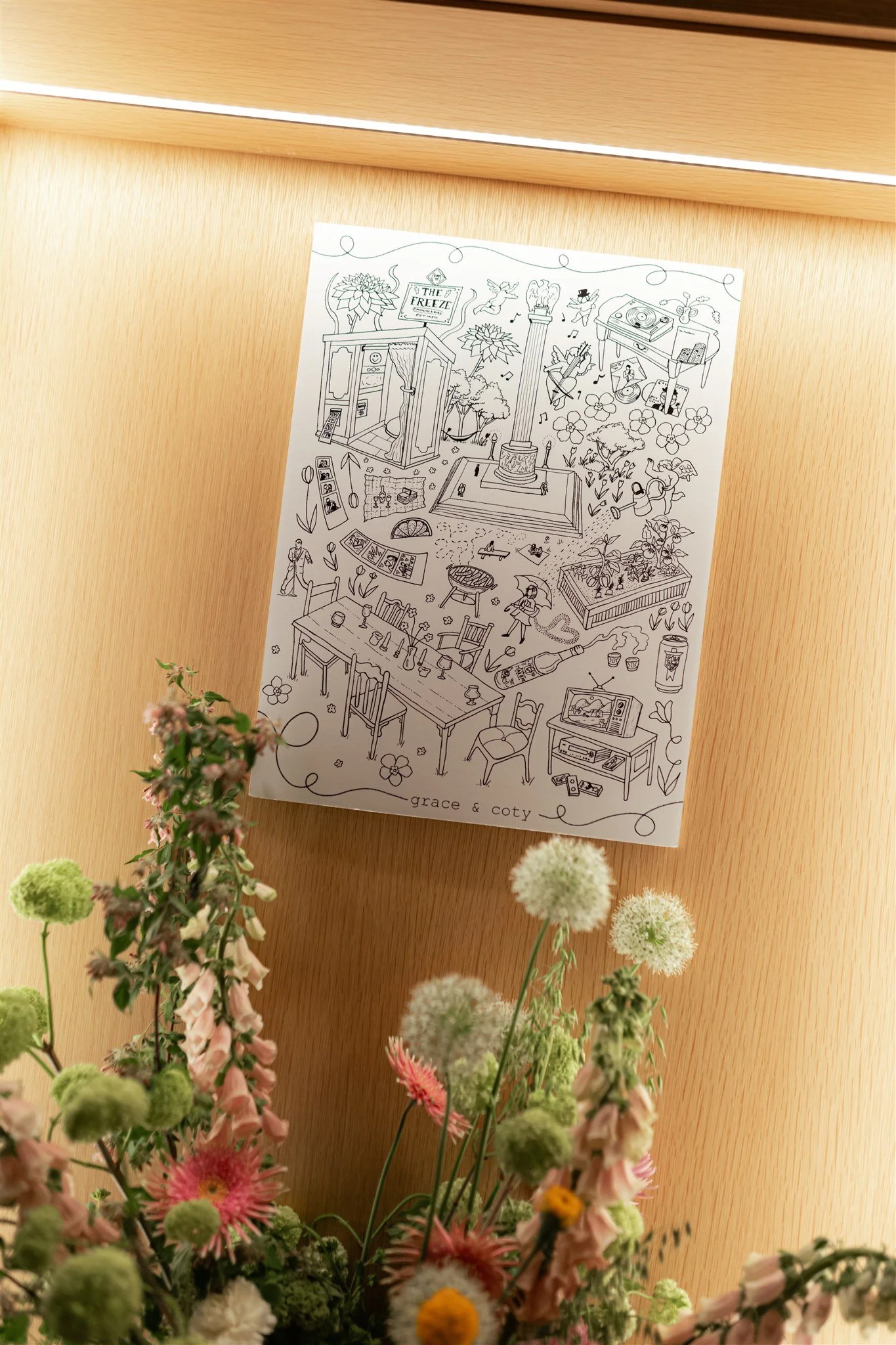 A black and white coloring sheet on a wooden surface with flowers and musical notes, titled 'Grace & Coty'