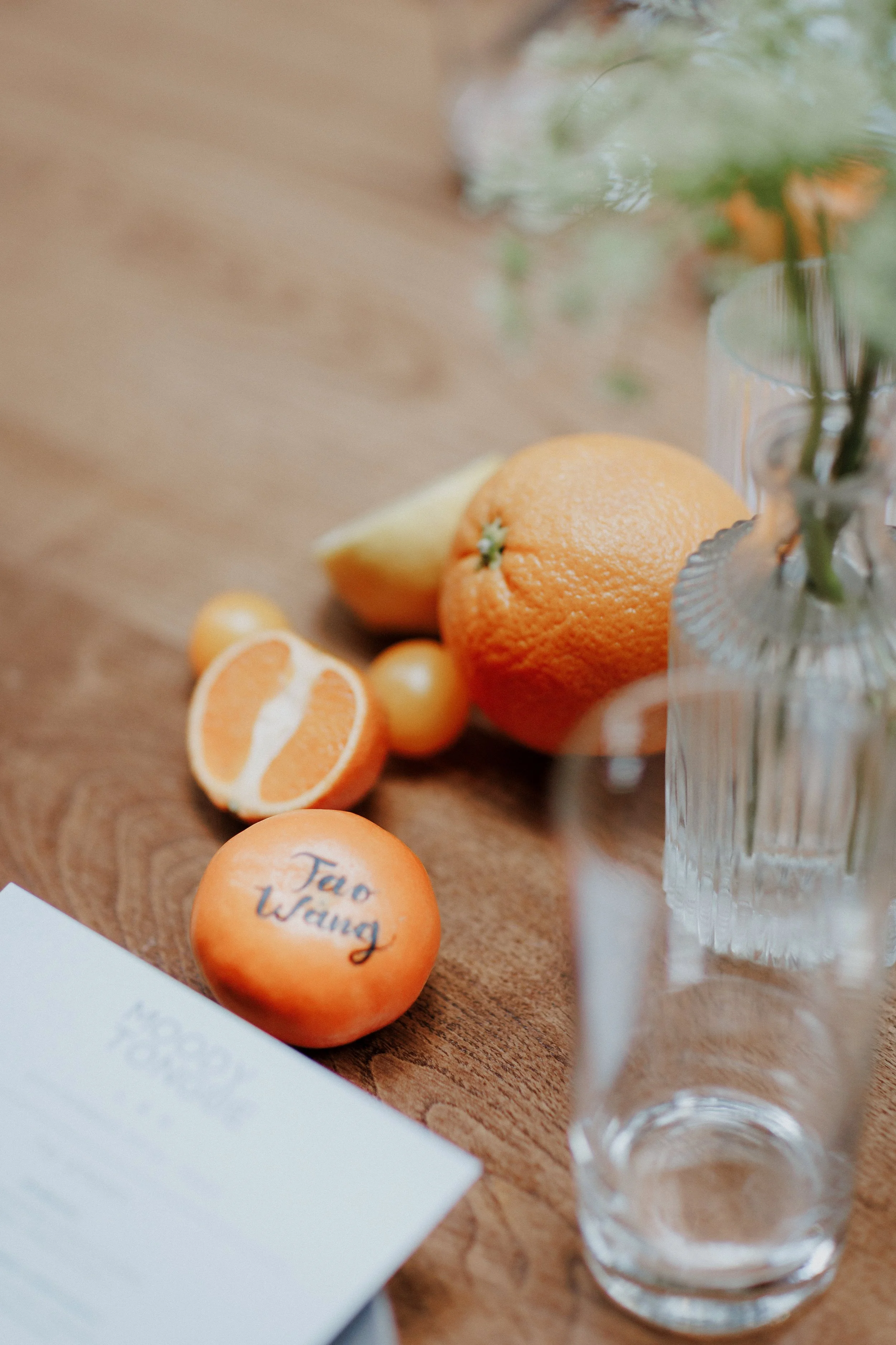 A glass of water and a pink-orange 'Top Waying' ball on a wooden surface.
