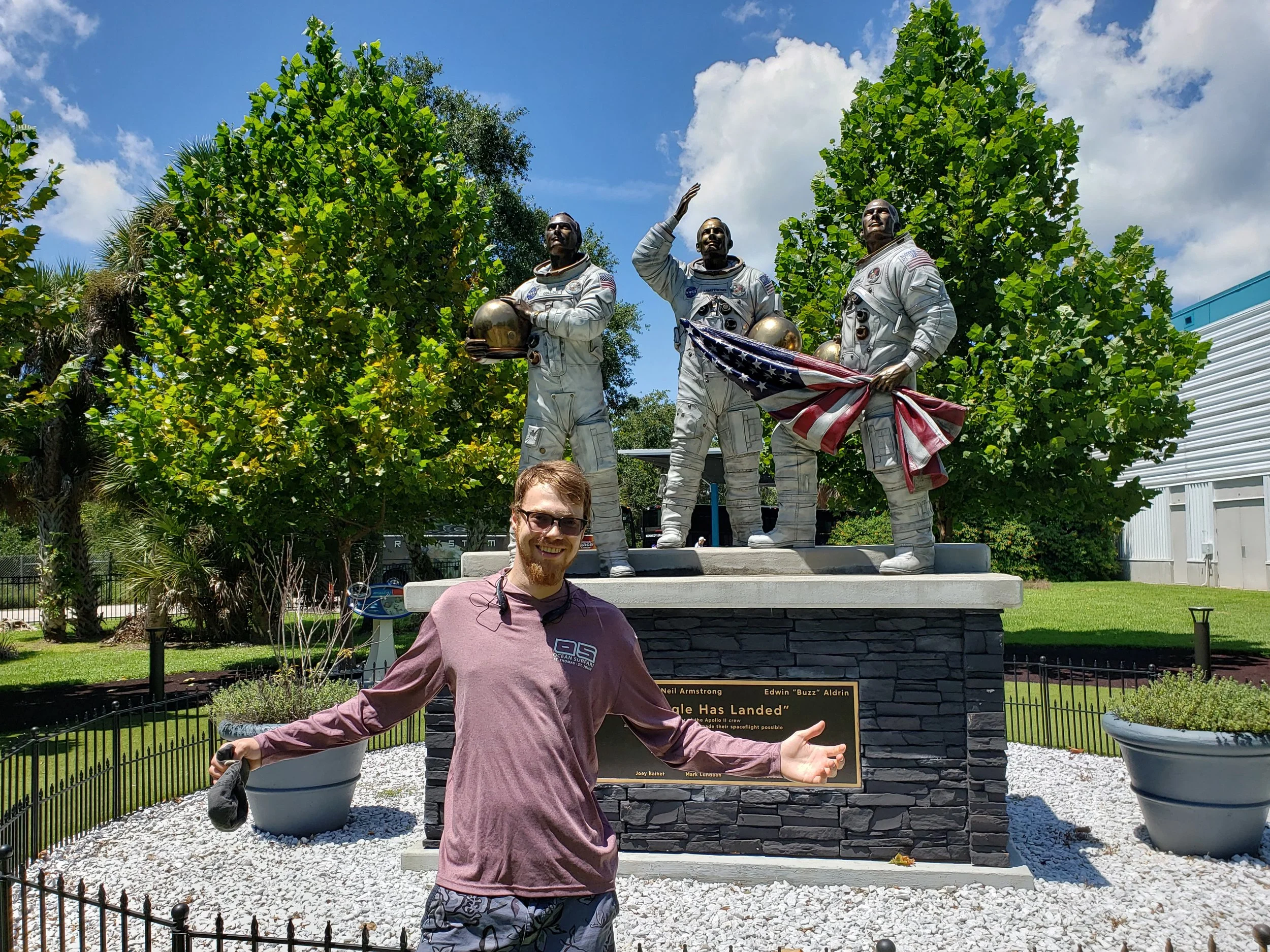Blaise Jorgensen, candidate for Washoe County Public Administrator, standing in front of a statue of three astronauts holding a flag and helmets.