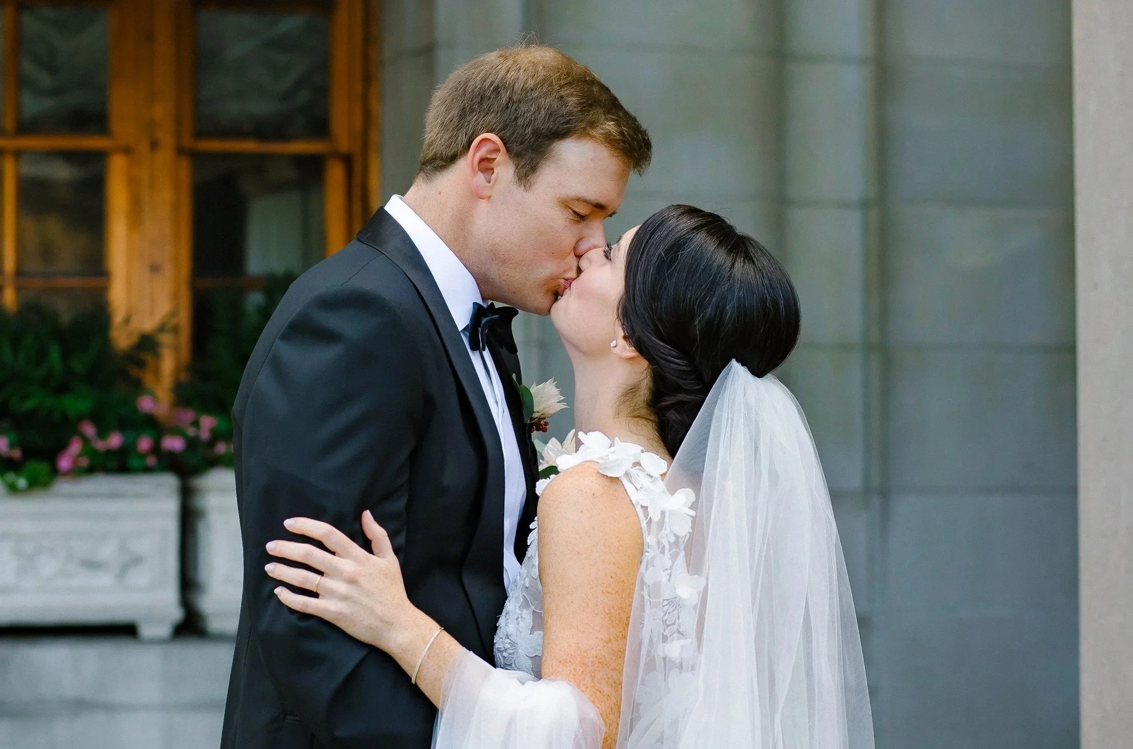 A bride and groom in wedding attire sharing a kiss.