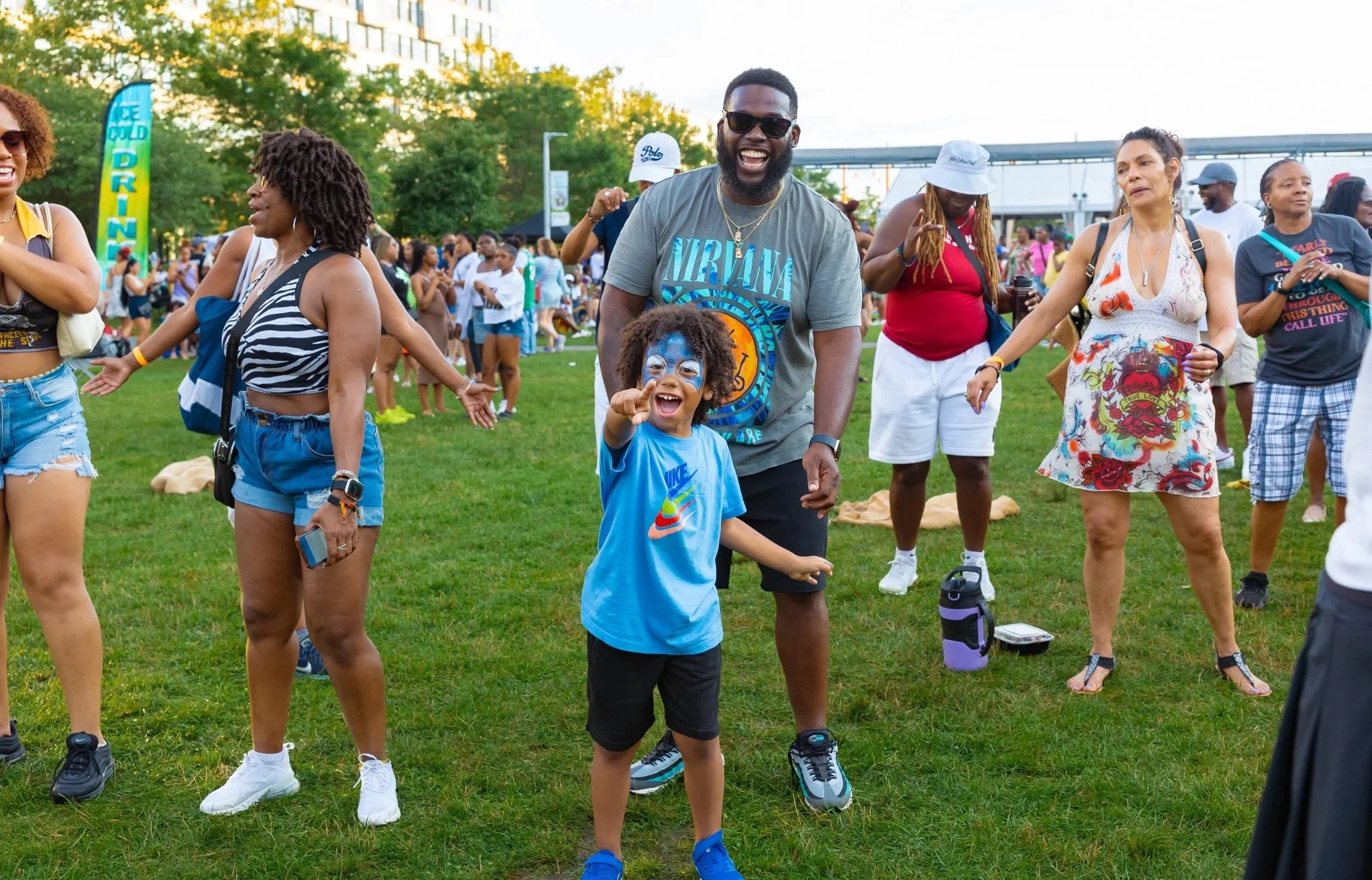 A group of people dancing and enjoying themselves outdoors on a grassy field during a lively event.