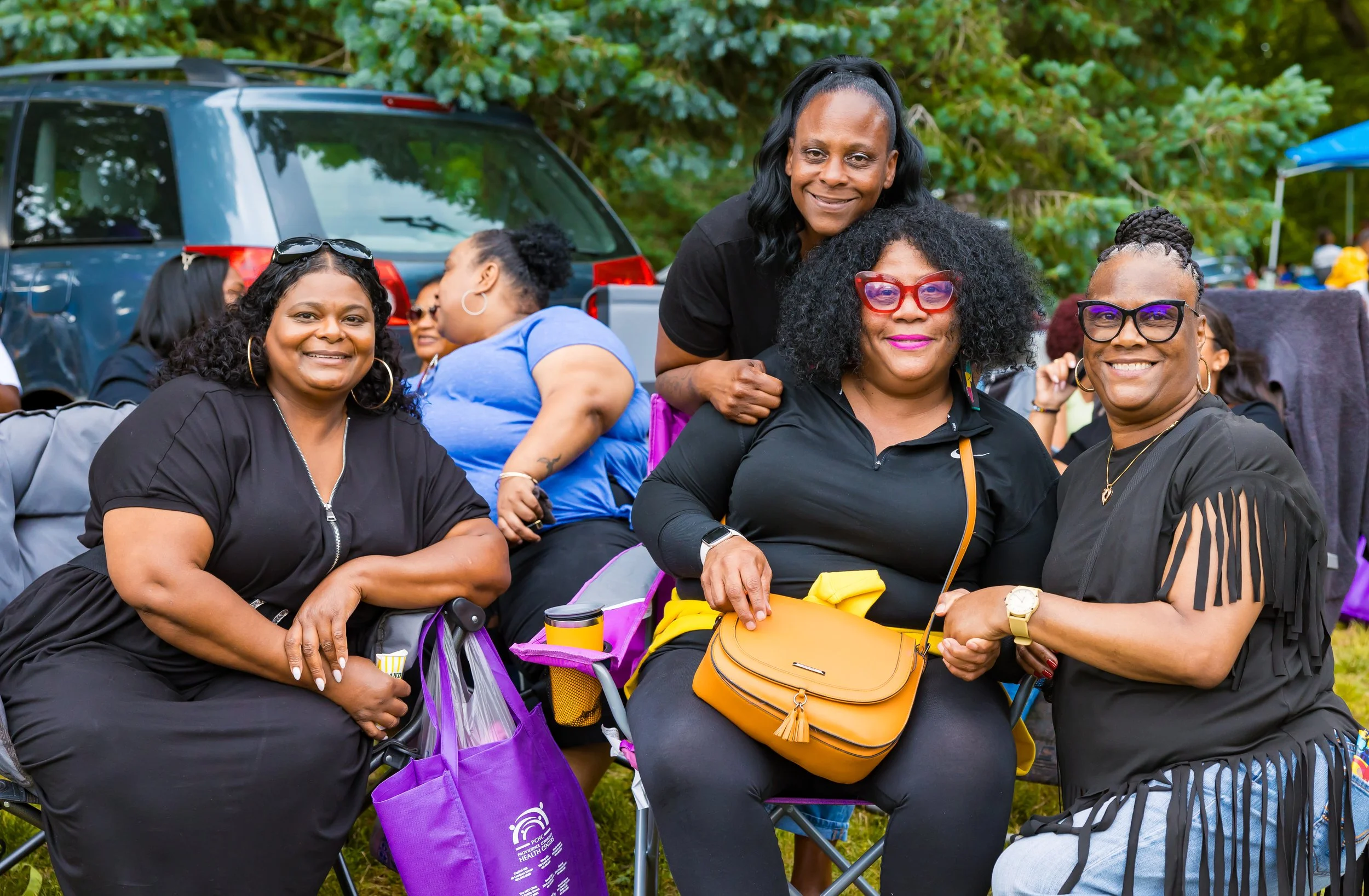 Group of Black women smiling at a outdoor gathering.
