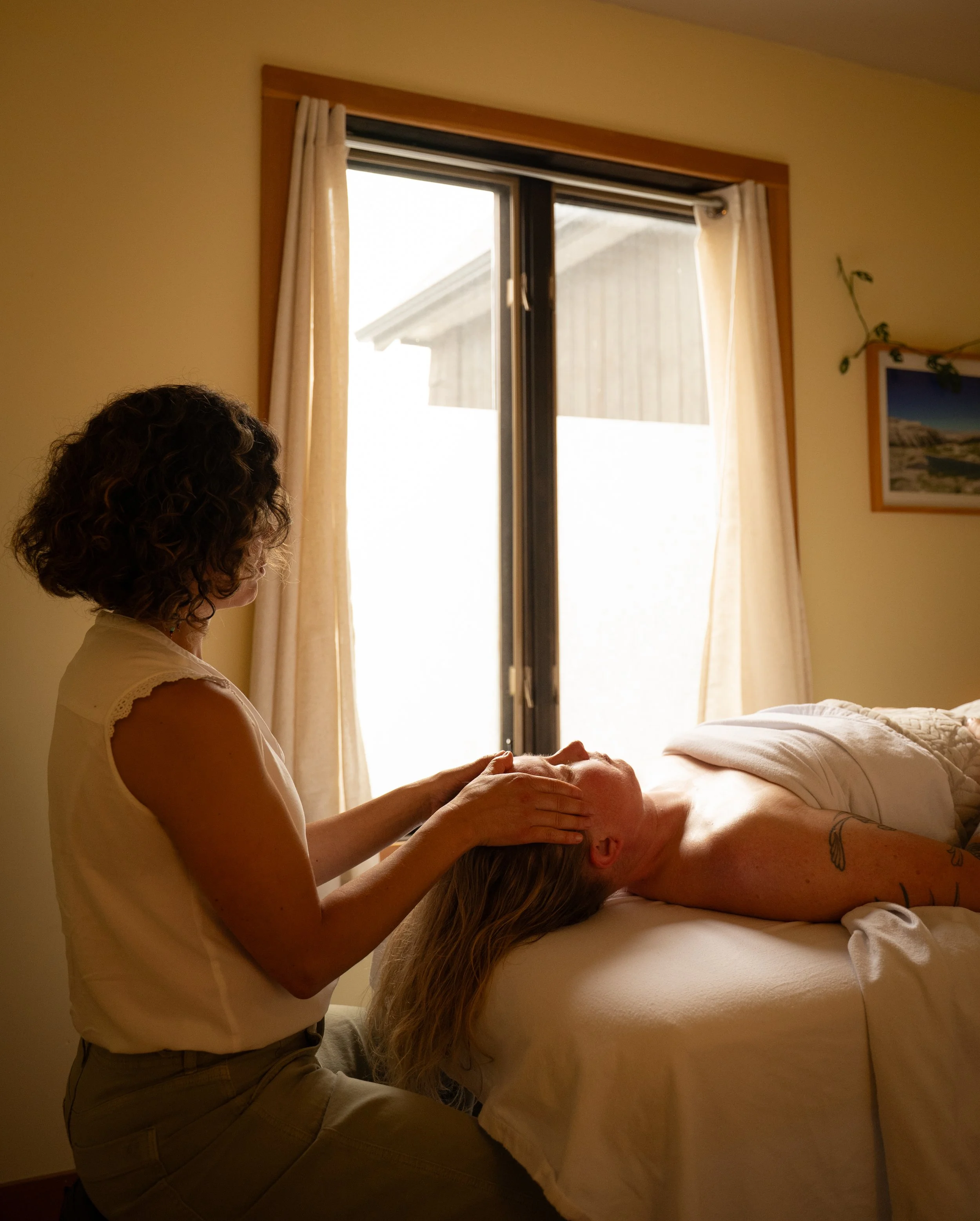 Female client receiving Reiki. Therapist's hands placed on client's forehead.