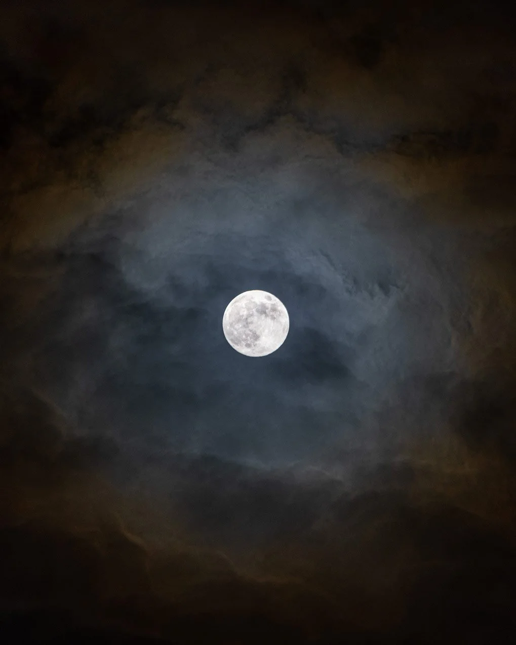 Full moon shining through a cloudy night sky.