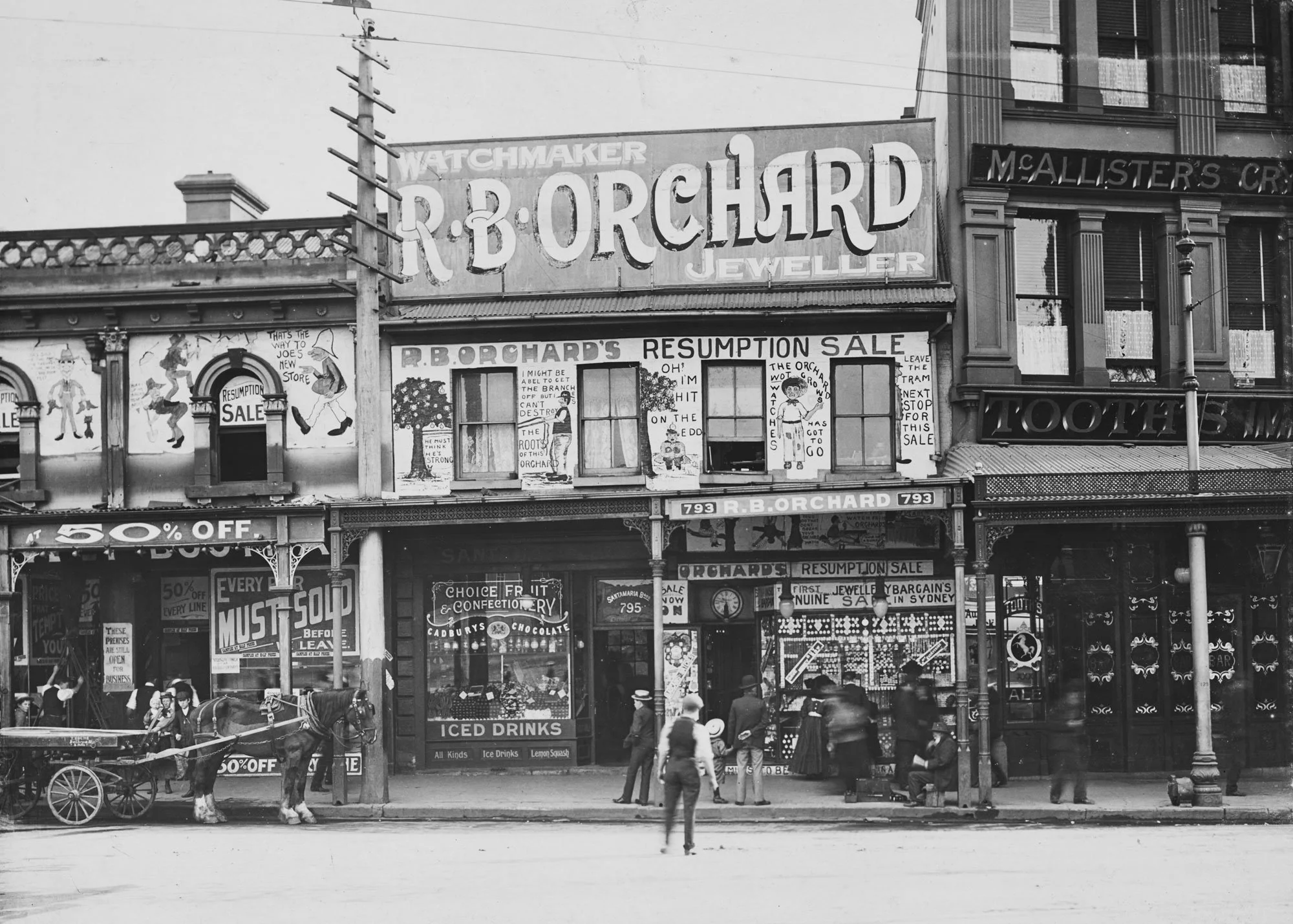 Black and white photo of a vintage storefront with signs for R.B. Orchard and resumption sale, people walking and horse-drawn carriage in front.