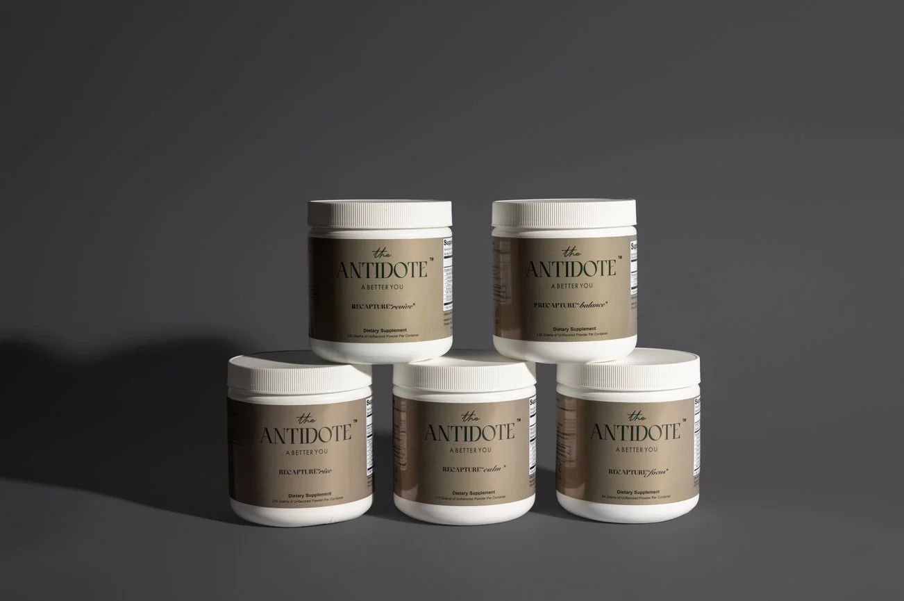 Five white containers of dietary supplements labeled 'Antidote' arranged in a pyramid shape against a gray background.