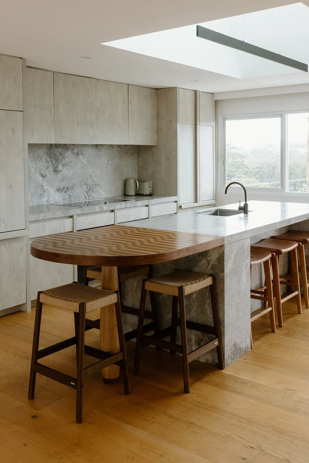 Modern kitchen design Central Coast with stone and timber finishes by Everyday Designs featuring marble island, a wooden breakfast bar and skylight.