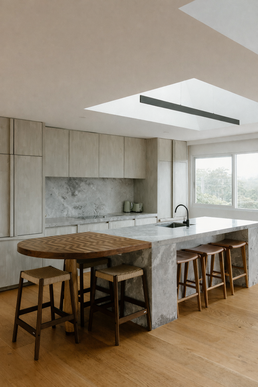 Modern kitchen with wooden cabinets, marble island with seating, large window, and skylight for natural light.
