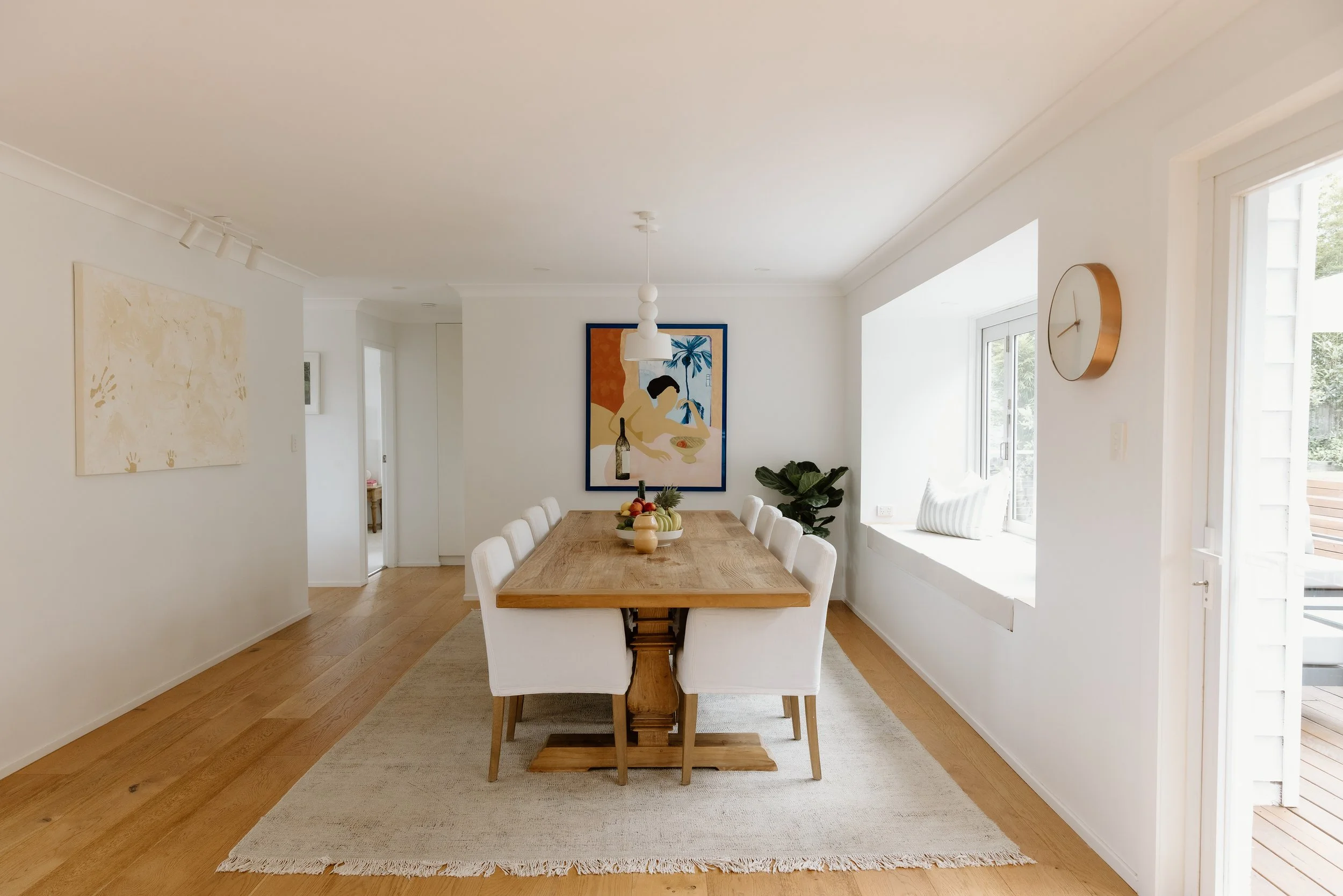 Dining and living space design Central Coast with timber, stone, artwork, and soft neutral palette.