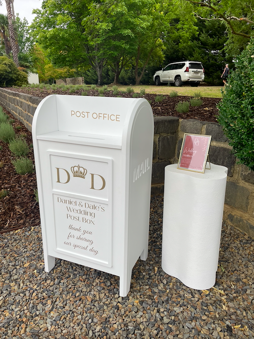 White collapsible wedding wishing well mailbox styled like a post box—used for collecting cards and messages at weddings and events. Customisable panel, flat-pack design, available for hire in Melbourne.