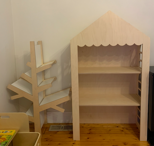 Freestanding dollhouse display shelf made from raw birch plywood with window cut-outs and scalloped trim. Features 3 shelves and pitched roof design. Ideal for events, kids’ rooms, or markets.