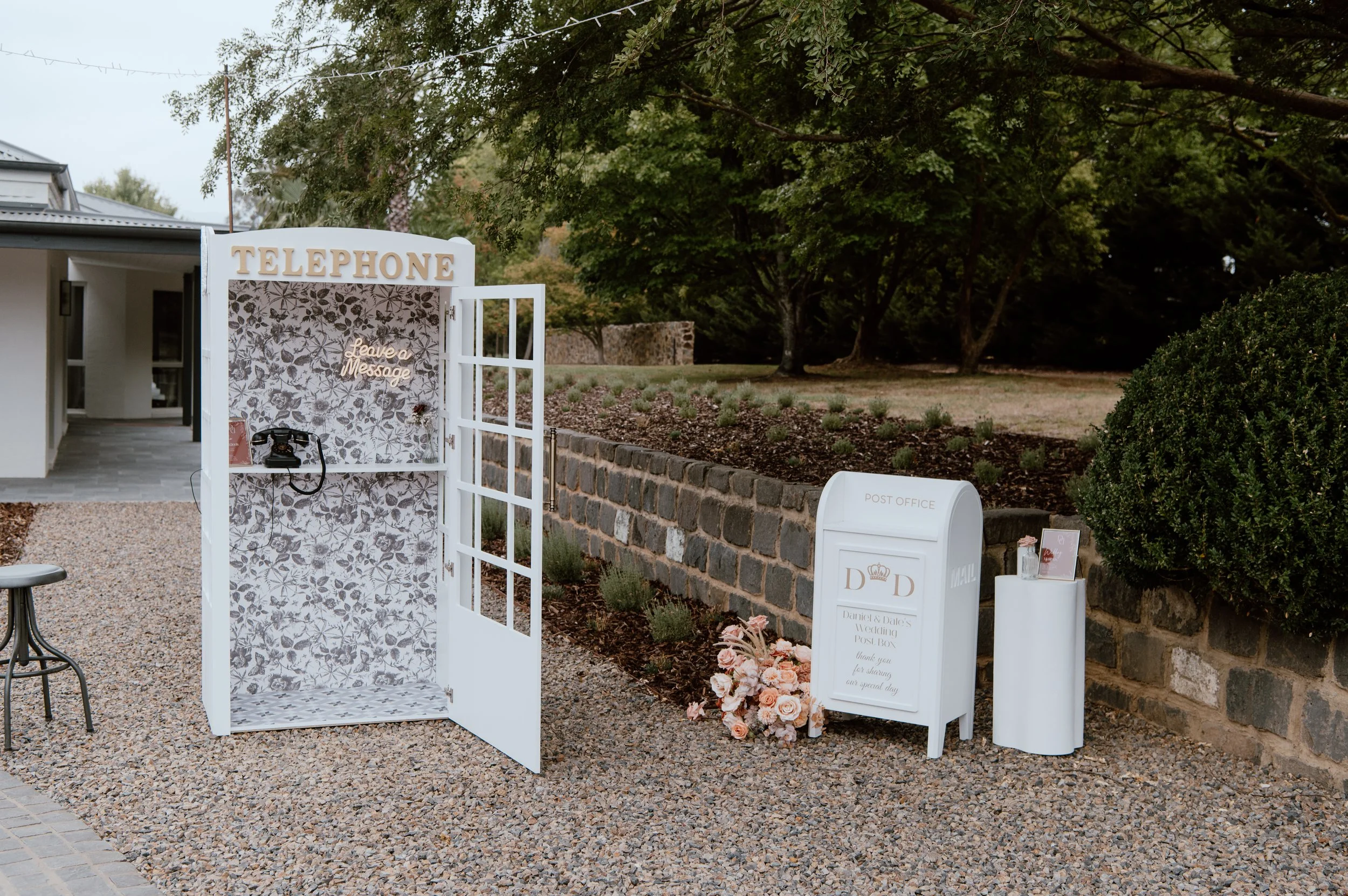 White collapsible telephone booth purchase with vintage rotary phone, floral wallpaper, brass handle, mirrored ceiling, tiled base, and 'Leave a Message' LED sign—perfect for weddings, parties, and audio guestbooks in Melbourne.