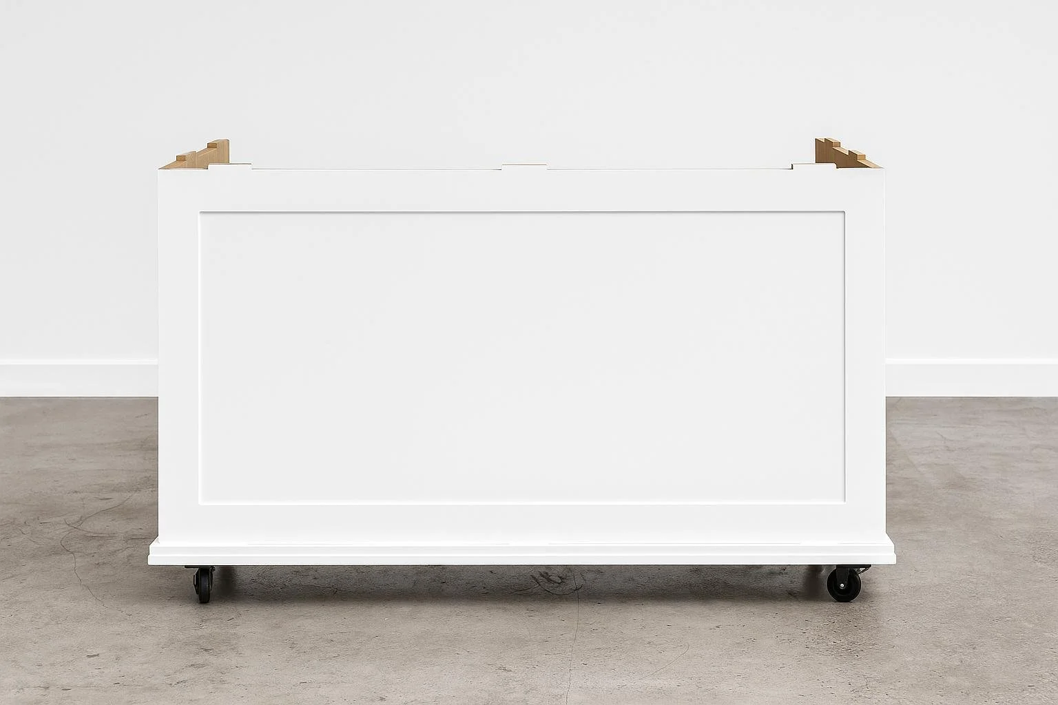 Empty white mobile island with wheels, set against a plain white wall and light-colored concrete floor.