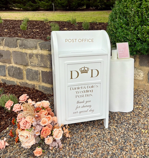 White collapsible wedding wishing well mailbox styled like a post box—used for collecting cards and messages at weddings and events. Customisable panel, flat-pack design, available for hire in Melbourne.