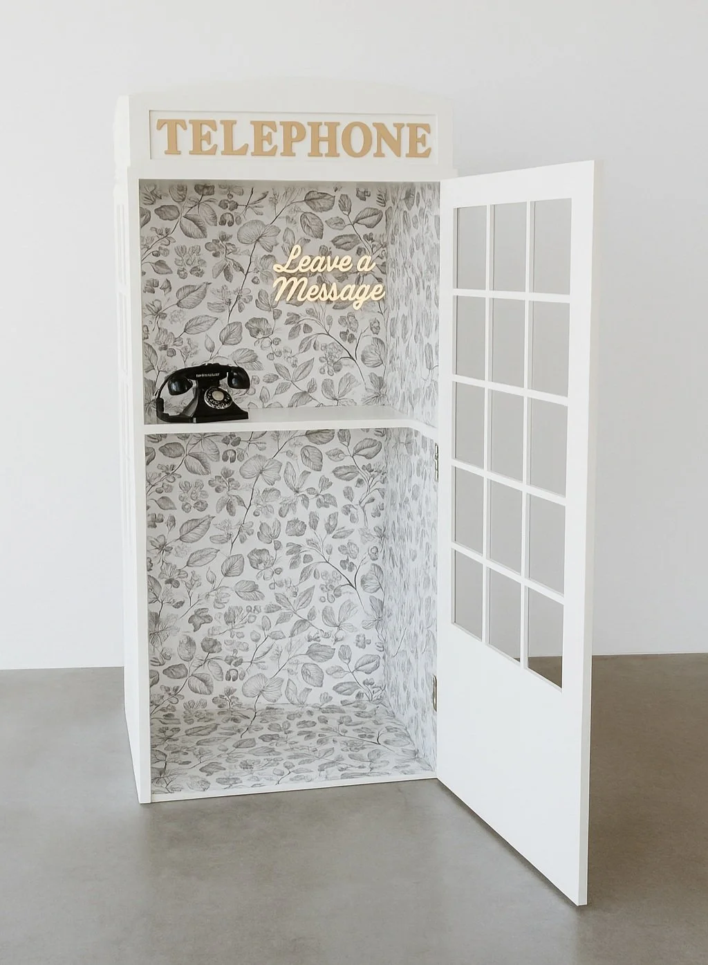 White collapsible telephone booth hire with vintage rotary phone, floral wallpaper, brass handle, mirrored ceiling, tiled base, and 'Leave a Message' LED sign—perfect for weddings, parties, and audio guestbooks in Melbourne.