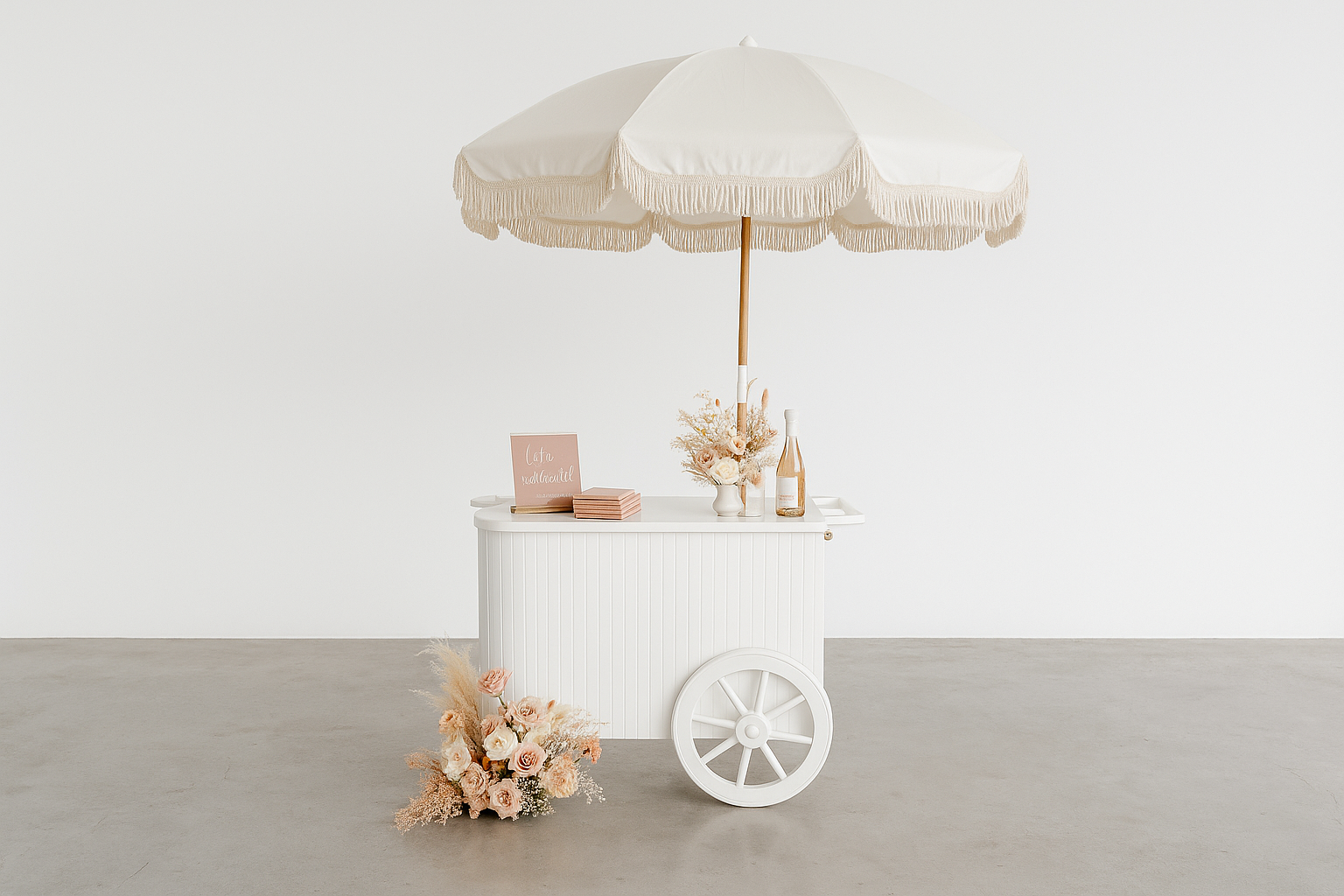 White vintage-style cart with a large white umbrella, pink roses and dried flowers on and nearby, bottles, and a small pink sign reading "Caffe romantique" against a plain white background.