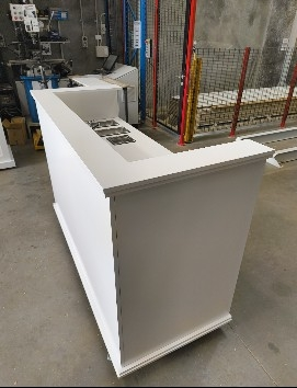 White reception desk with built-in computer monitor and keyboard in a warehouse setting.