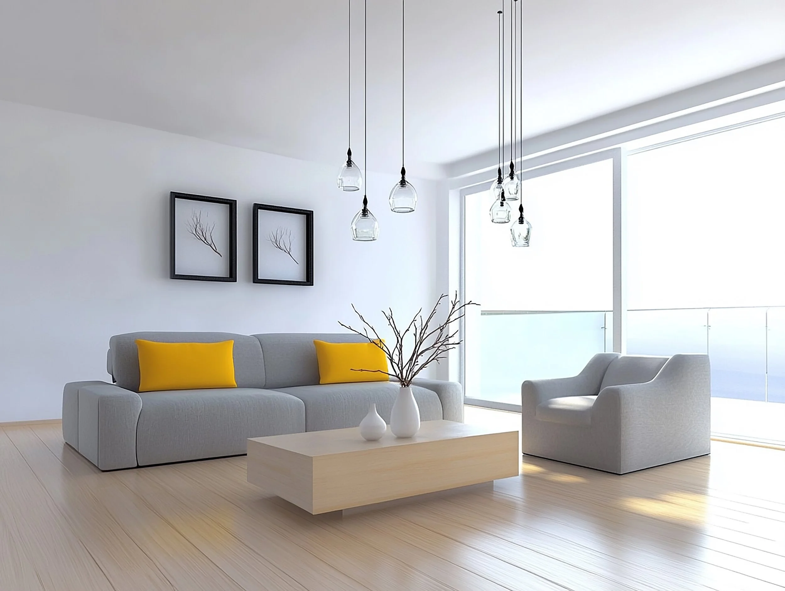 Minimalist living room with a gray sofa with yellow pillows, a matching armchair, a wooden coffee table with white vases and branches, large windows with blinds, and framed artwork on white walls, all in a bright space with light wood flooring.