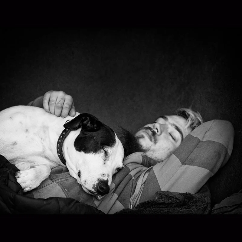 Ein Mann schläft mit einem Hund auf einem Sofa.