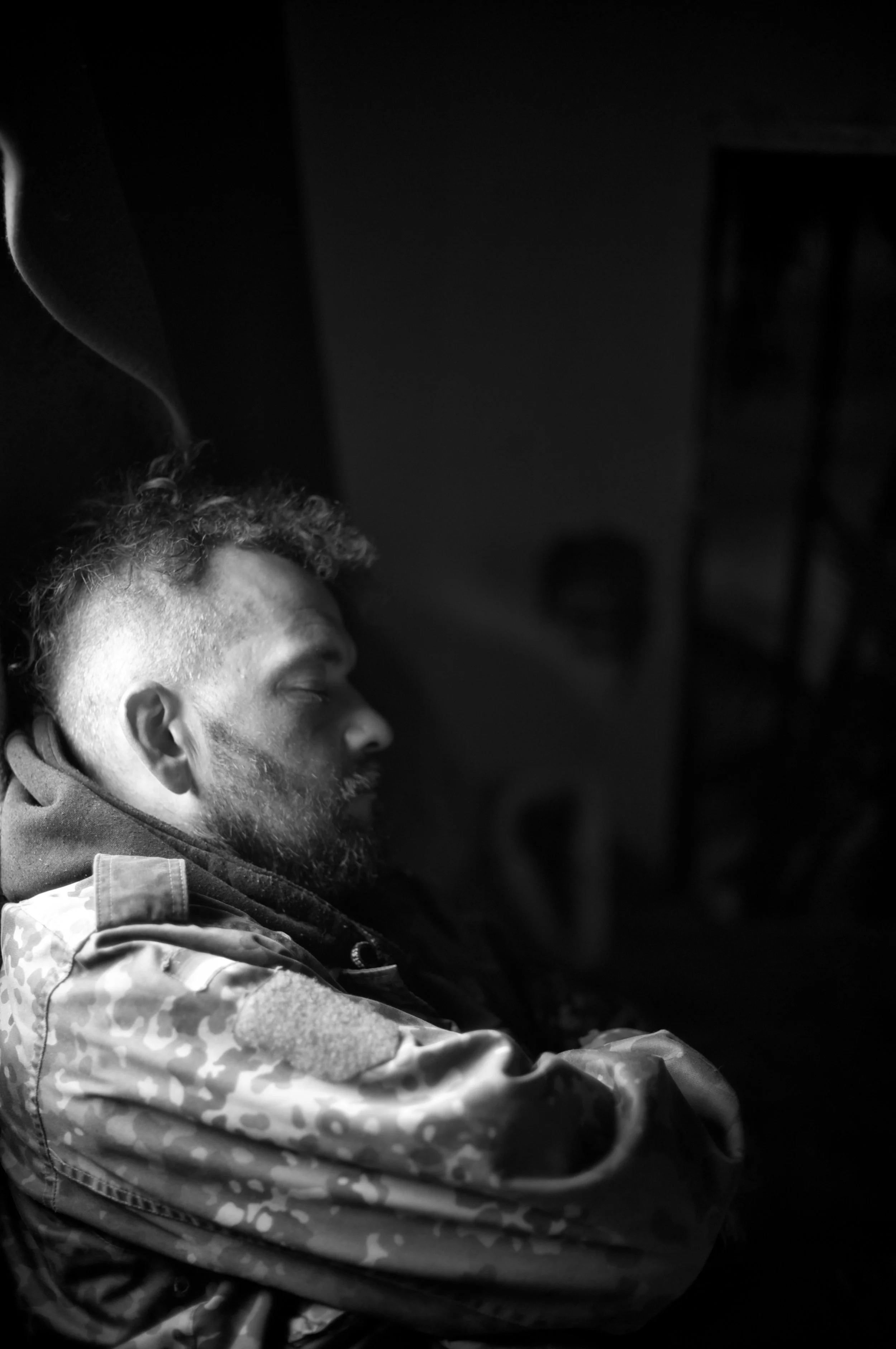 Schlafender Mann sitzt in Dunkelheit, Nahaufnahme, Schwarz-Weiß-Fotografie