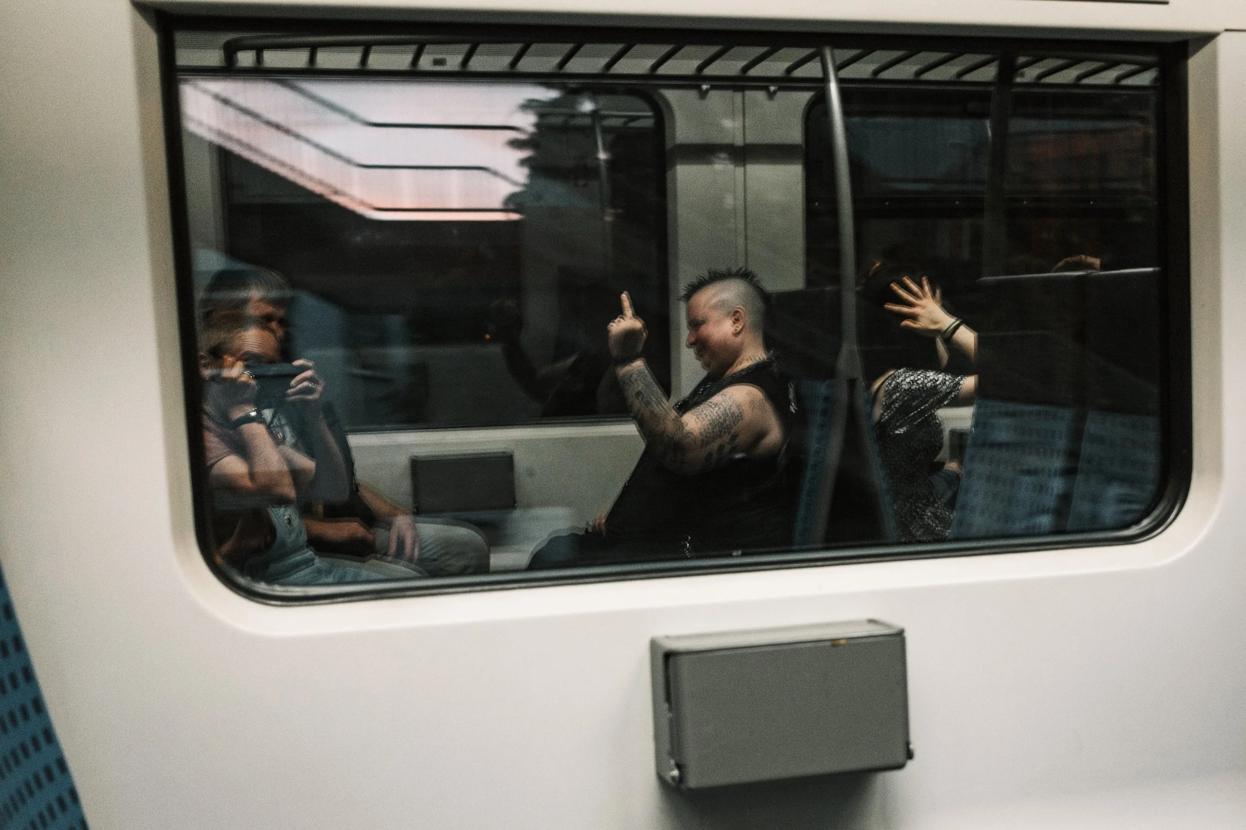 Menschen sitzen in einem Bus, einer macht eine Geste mit der Hand, während die andere Person ein Foto macht.