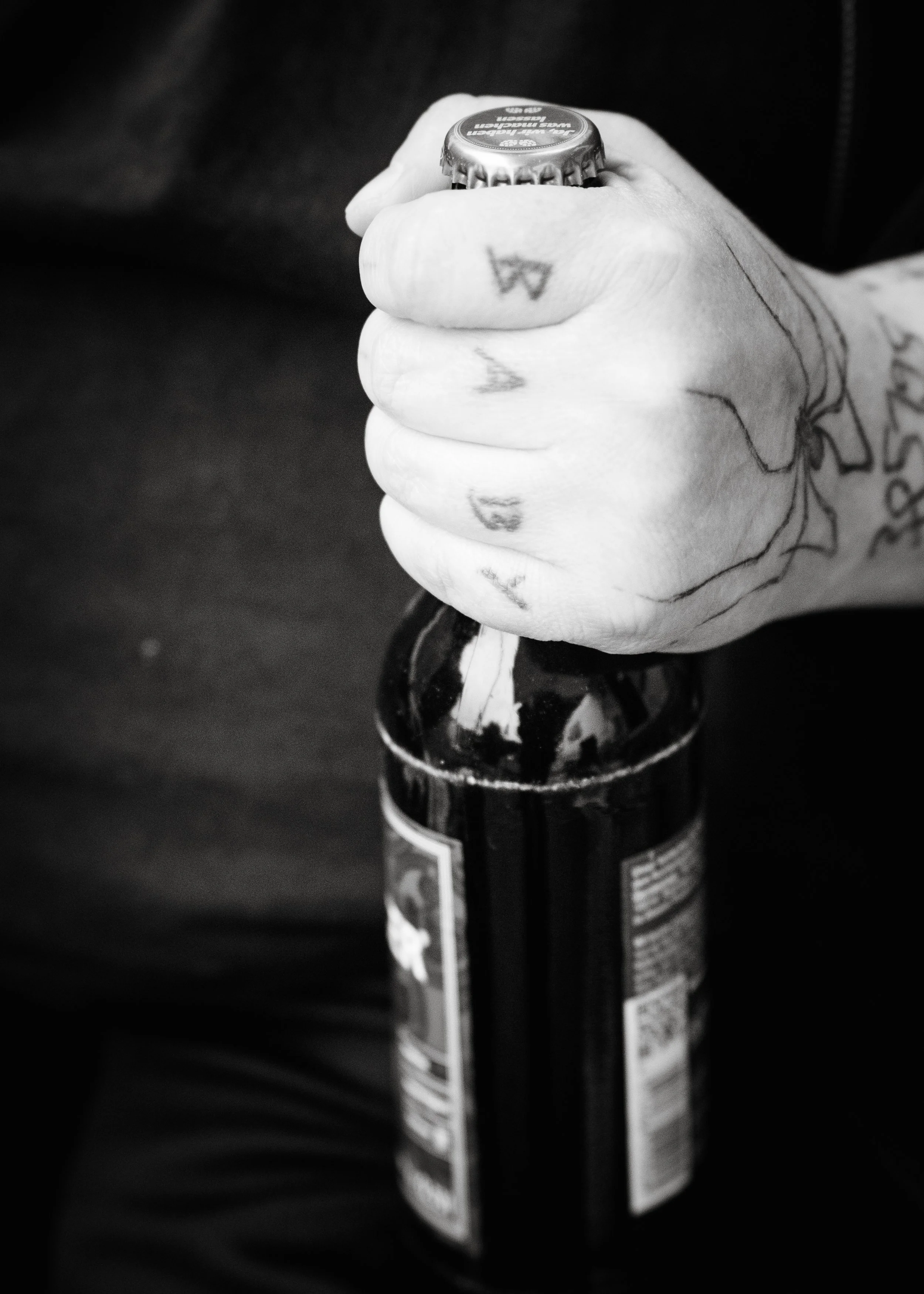 Eine Hand hält eine Flasche, vermutlich ein alkoholisches Getränk, in schwarz-weiß.