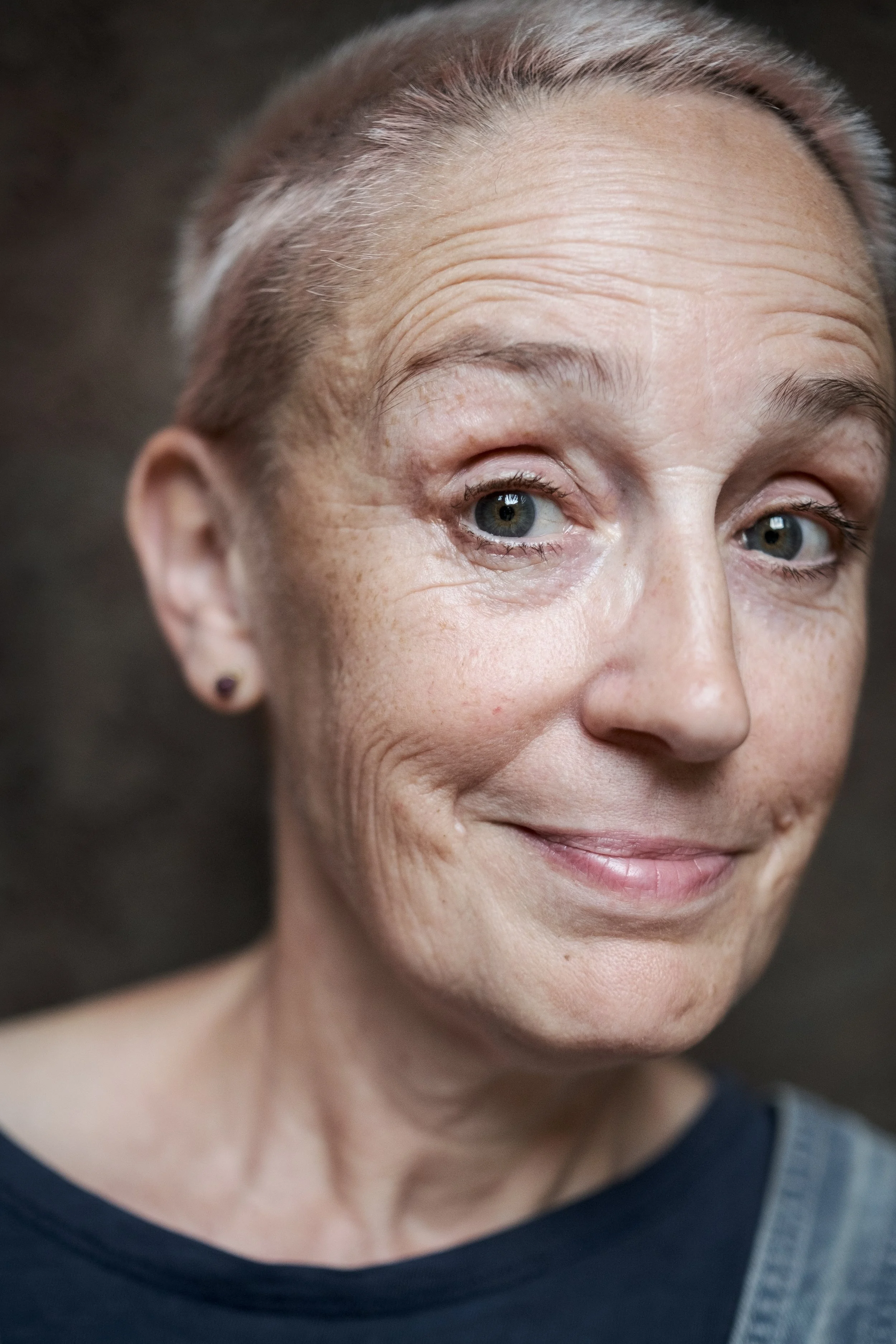 Nahaufnahme eines lachenden älteren Mädchens mit kurzen, grauen Haaren und Sommersprossen, das in die Kamera schaut.