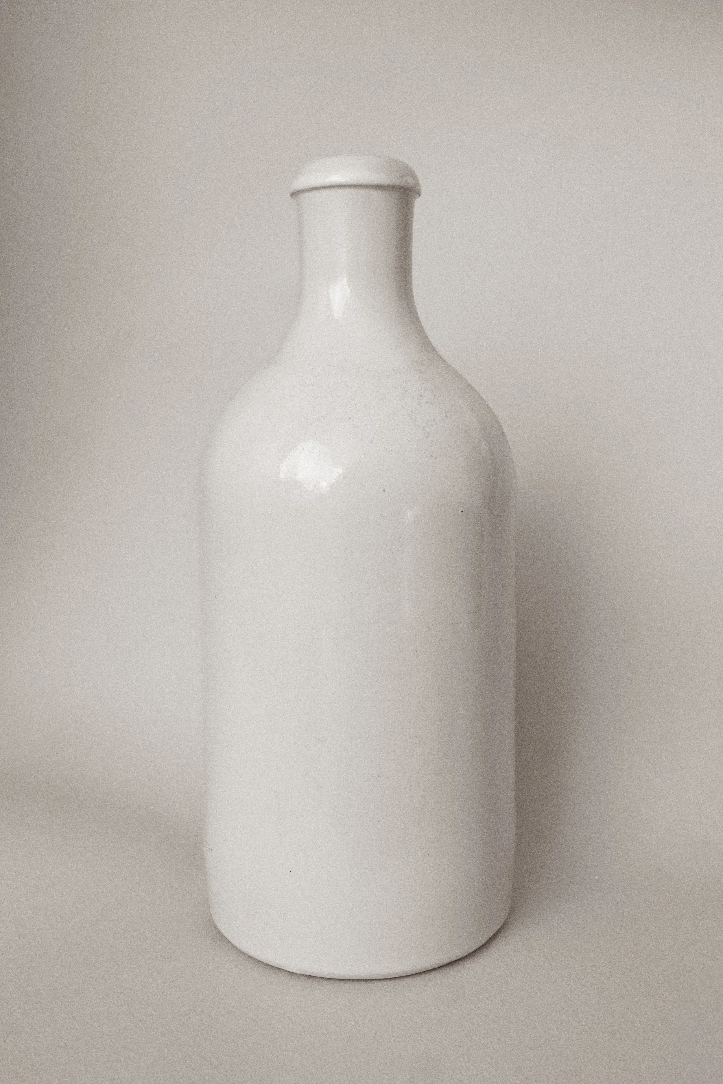 Weiße Keramikflasche auf neutralem Hintergrund.