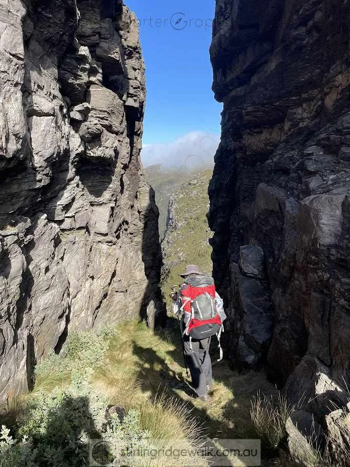 A walker passing through Central Gully, tightly enclosed between Central Buttress and North Buttress. 2nd Arrow is visible directly ahead in the centre of the photograph.