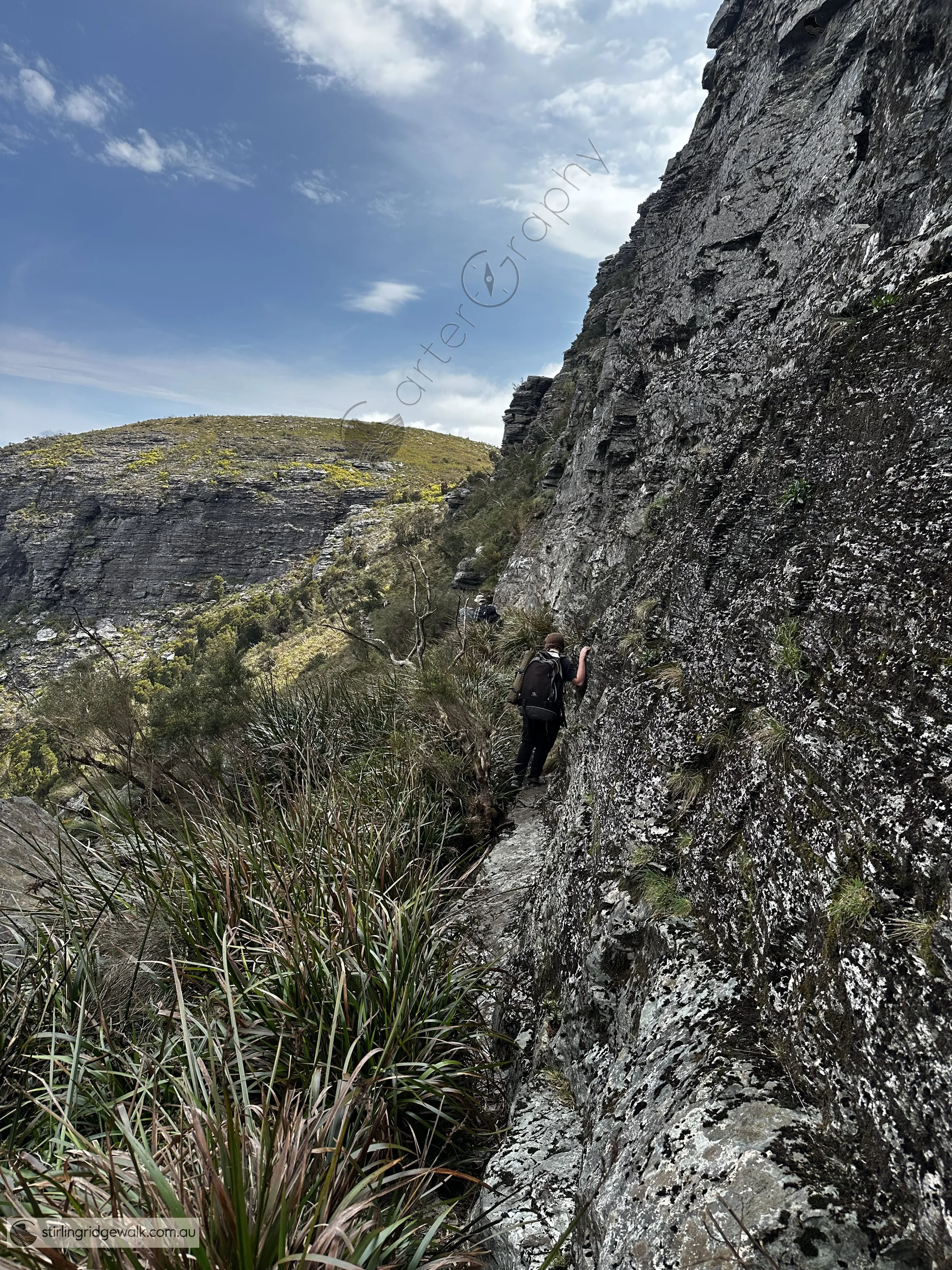 Following the narrow traverse along the southern face of Pyungoorup Peak towards 3rd Arrow, with the track squeezed between the imposing rock wall and steeply falling terrain. Baker’s Knob is visible in the background.
