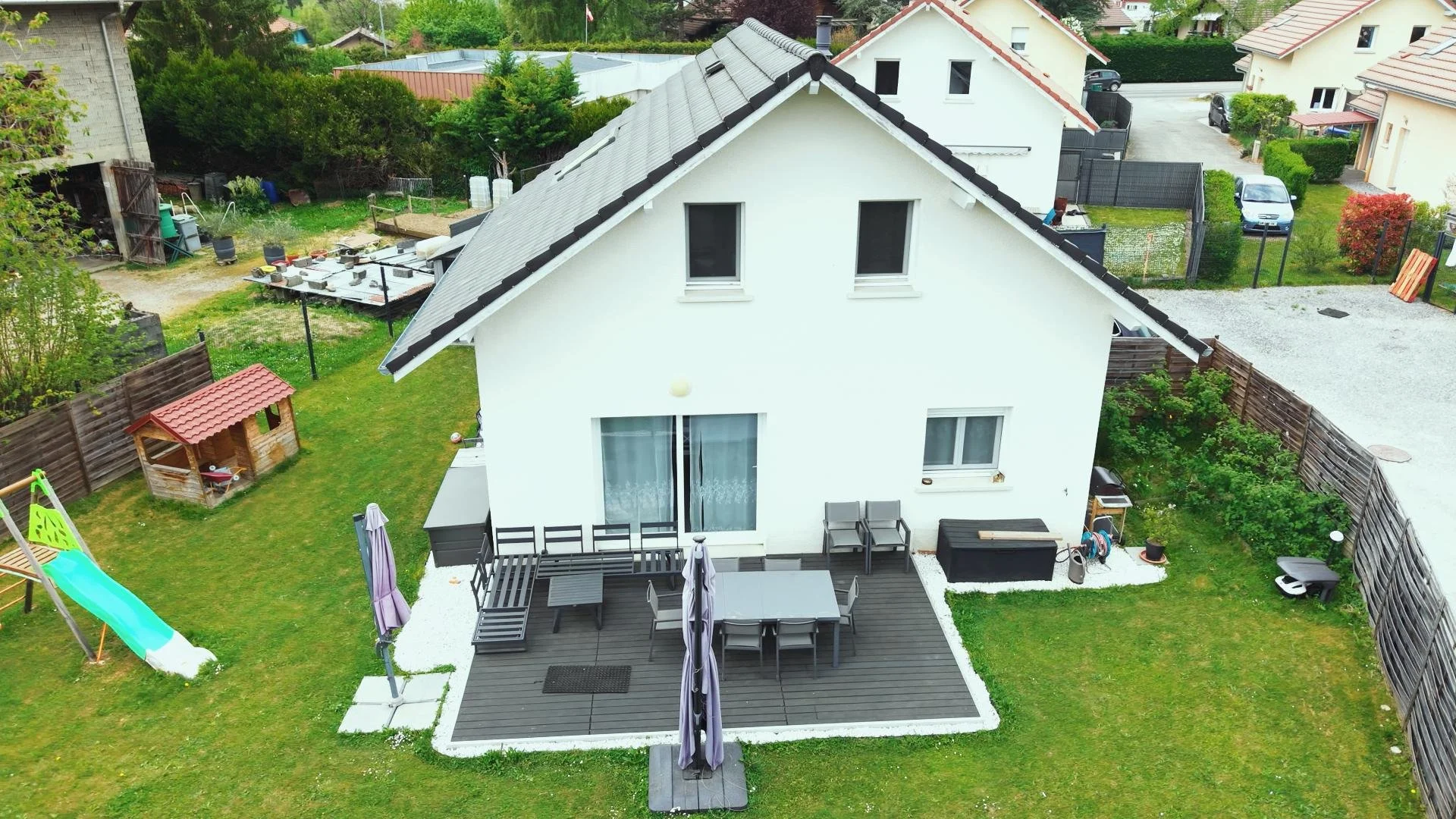 Vue aérienne par drone pour annonce  d'une maison blanche avec une terrasse en bois