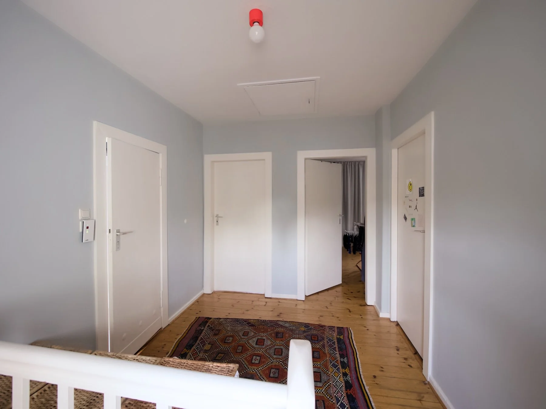 Ausgangssituation: ein ungemütlicher Flur im Obergeschoss mit weißen Wänden und defekter Deckenbeleuchtung 
Umsetzung: leichtes Farb- und Möblierungskonzept mit antikem Kelim, moderner Deckenleuchte und maßgefertigtem Raffrollo