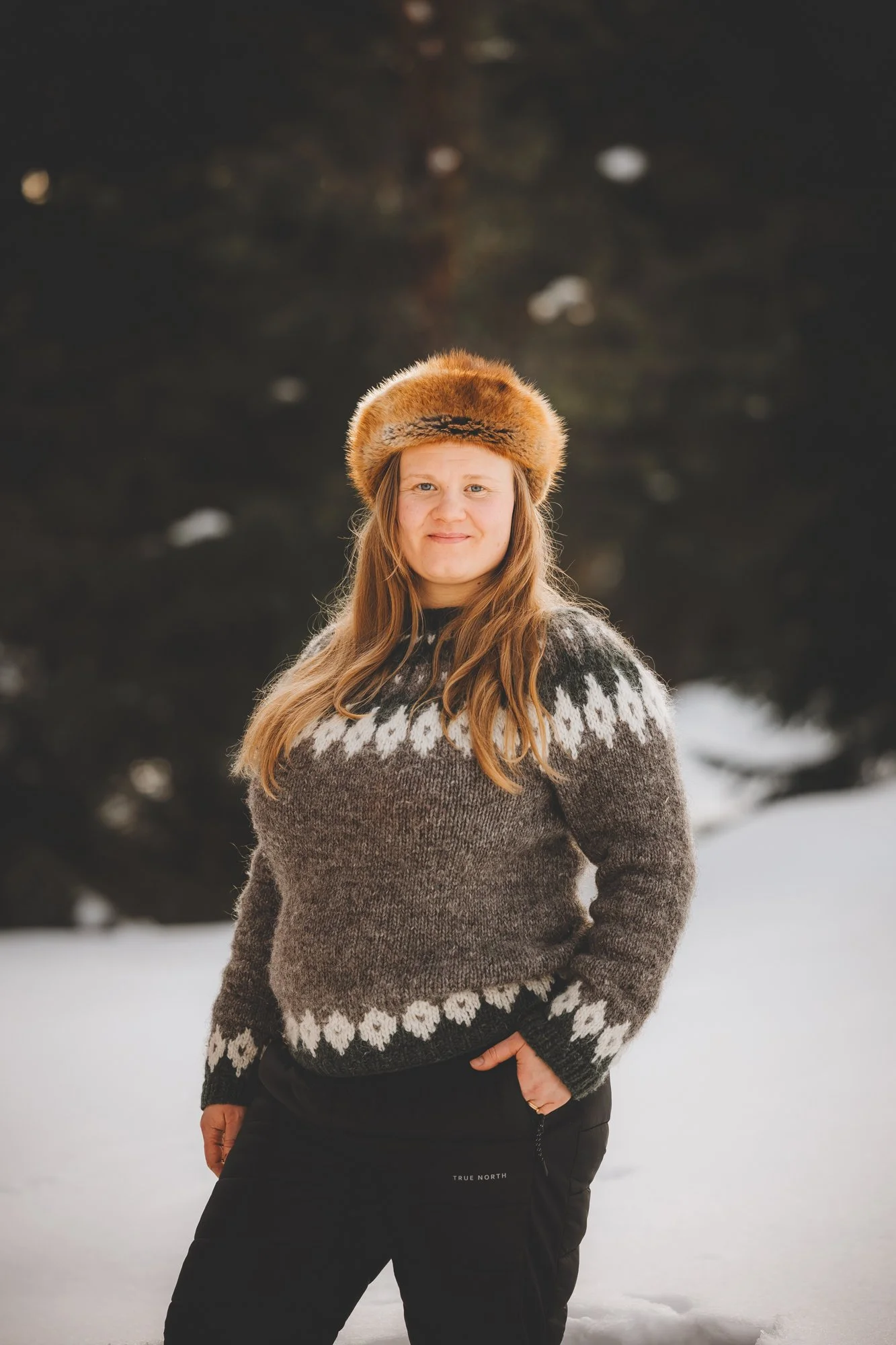 Kuva, jossa Kristiina hymyilee karvalakki päässä ja yllään villapaita.