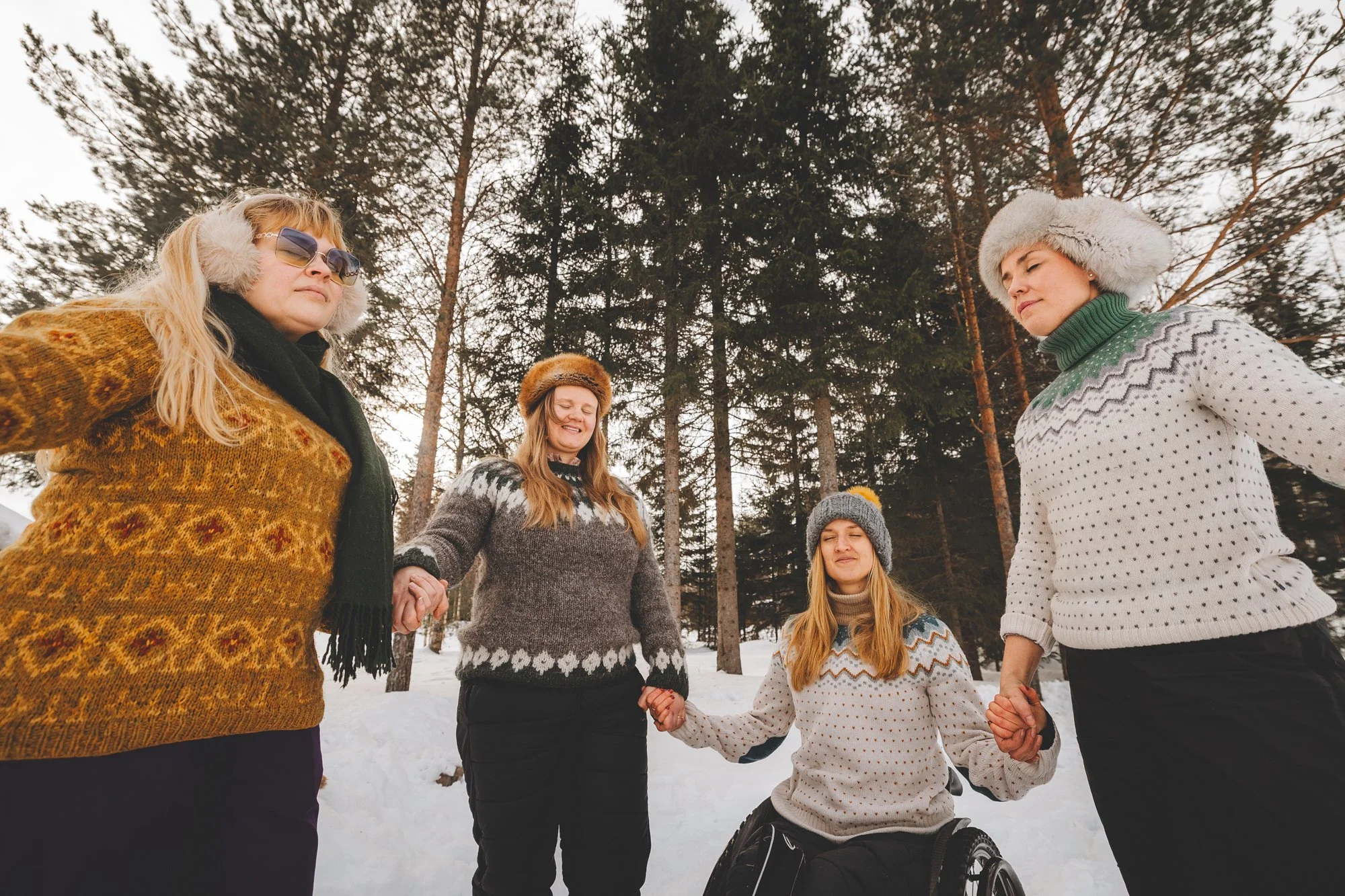 Kuva, jossa neljä naista on piirissä kädet toistensa käsissä, silmät kiinni.