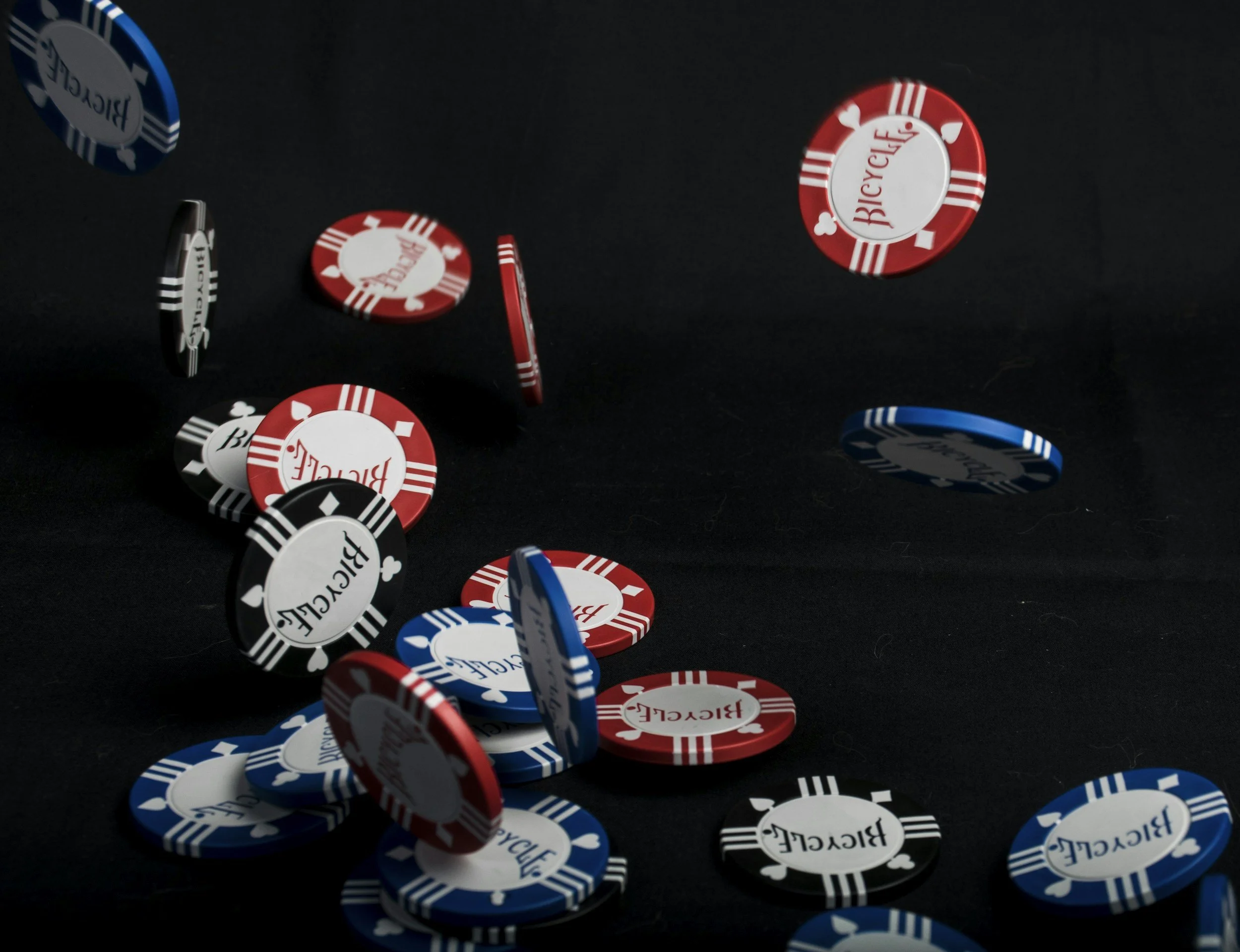 Spilled poker chips in red, blue, black, and white colors on a dark surface.
