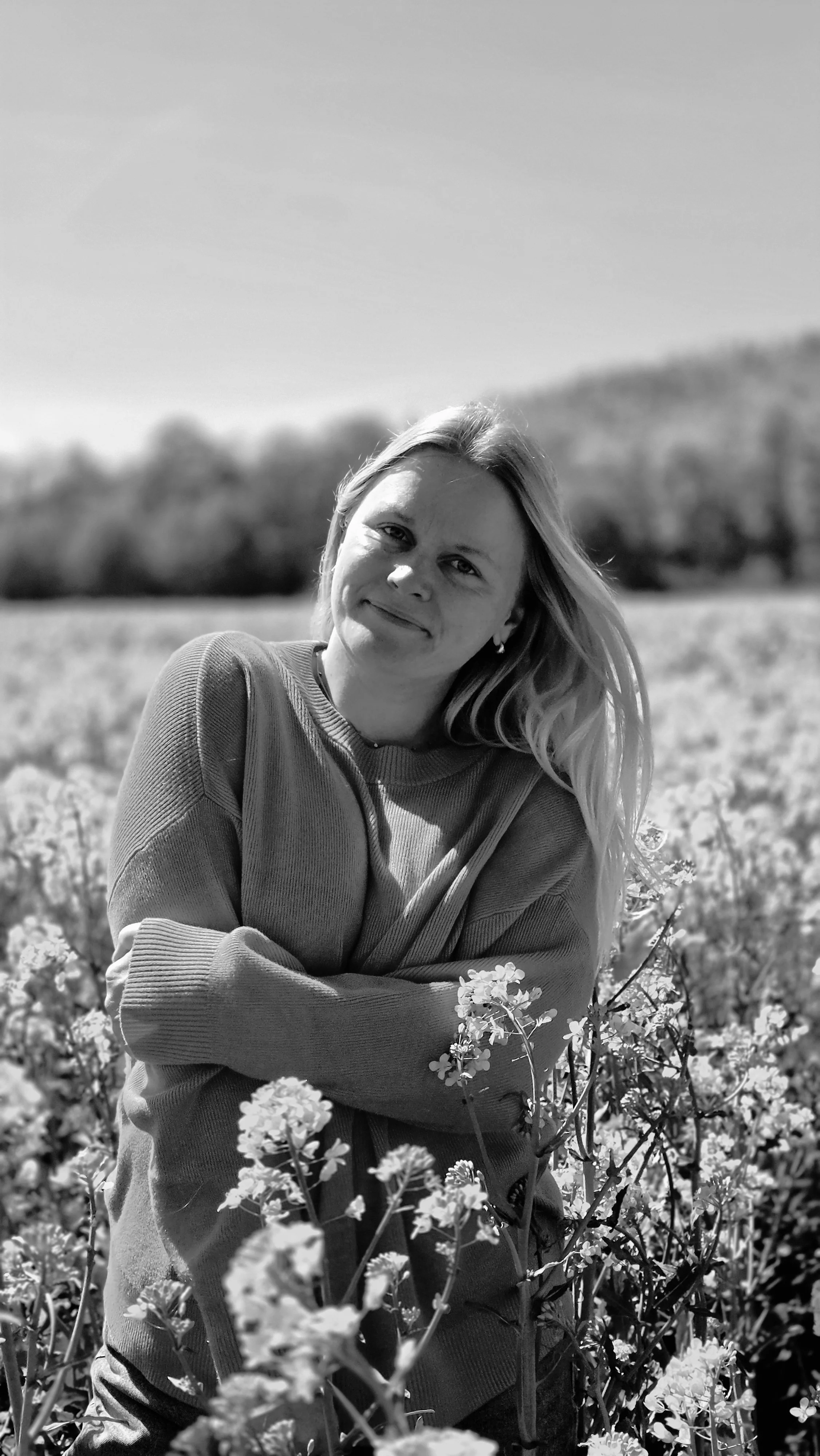 Schwarz-Weiß-Portrait von Saskia in einem Blumenfeld in der Lüneburger Heide.