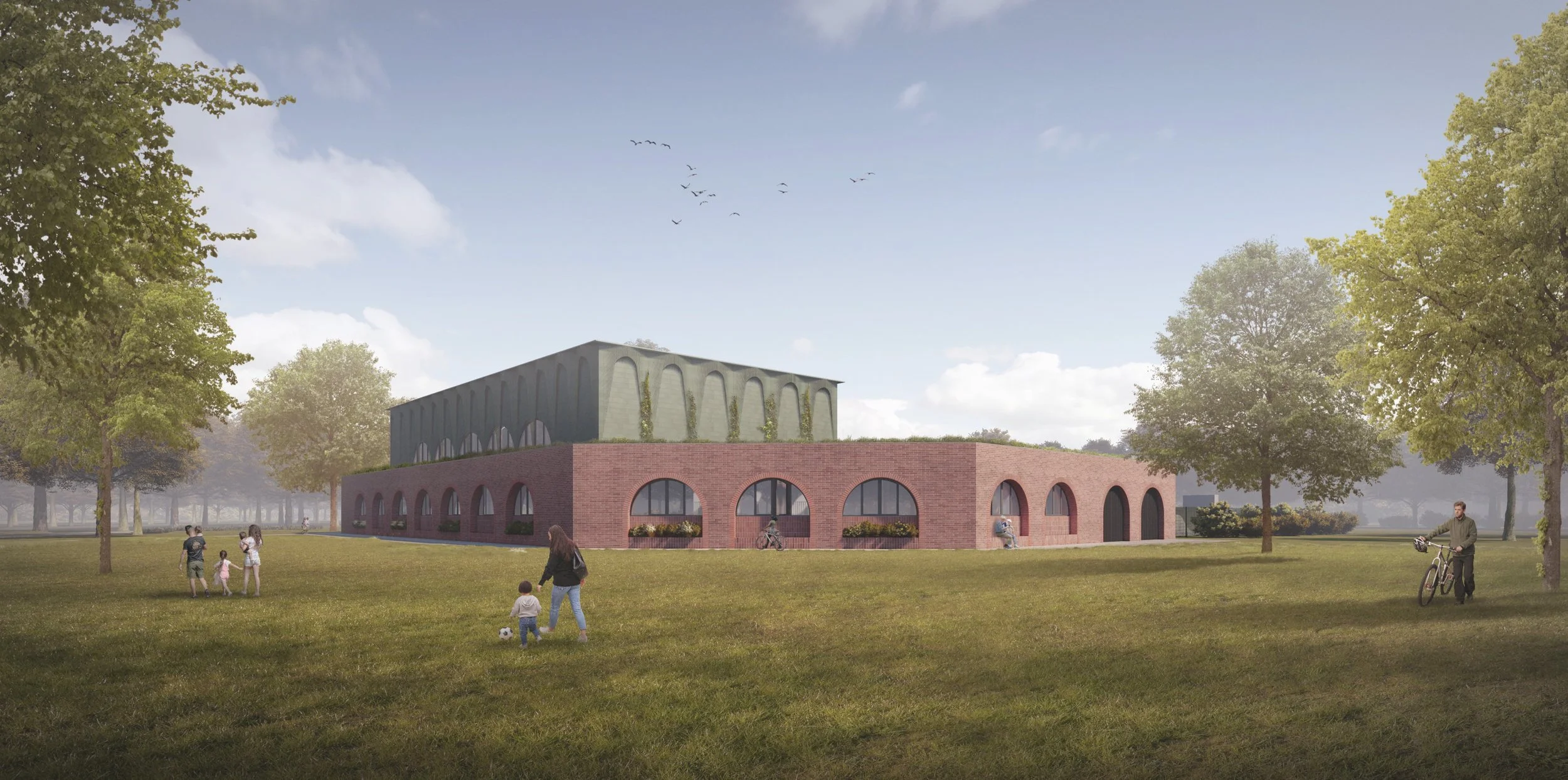 A modern mixed-use building with a brick lower level and a green upper level, set in a park with trees and people walking, playing, and biking, under a partly cloudy sky.