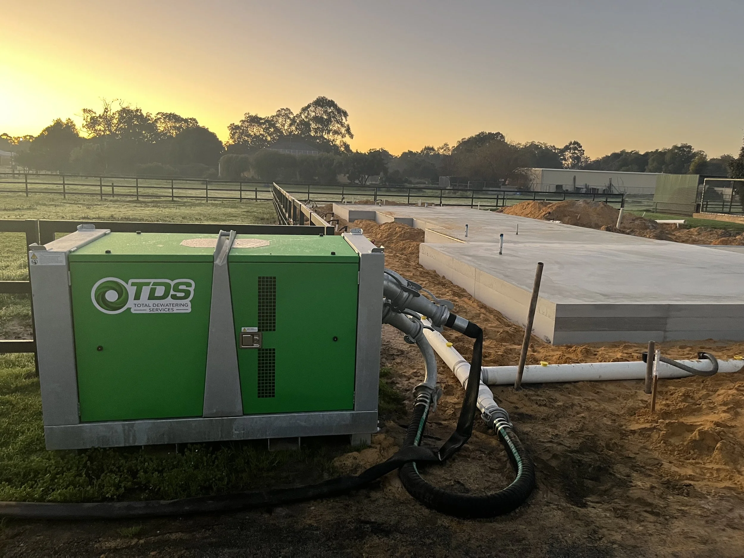 TDS wellpoint dewatering pump connected to groundwater control pipework beside a concrete building slab