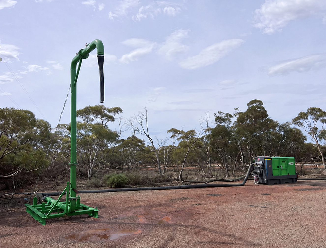 Water extraction equipment in a rural outdoor setting with trees and a blue sky.