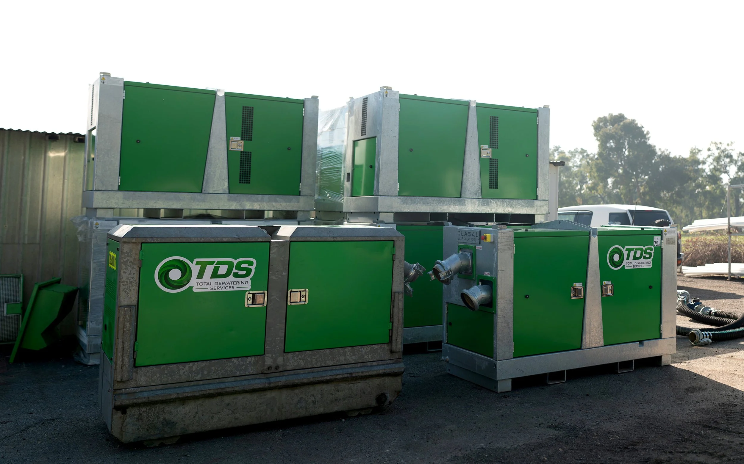 Multiple green industrial dewatering units with pipes and vents, branded TDS, outdoors on gravel ground under a clear sky.