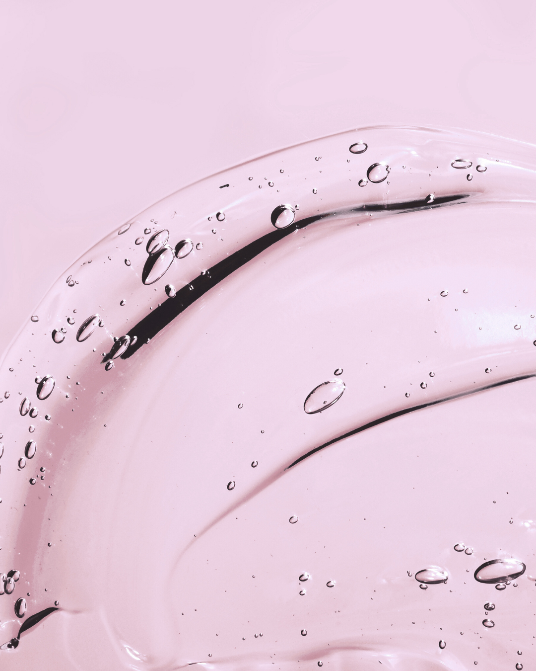 Close-up of a pink, glass clock face with black hands and water bubbles inside.