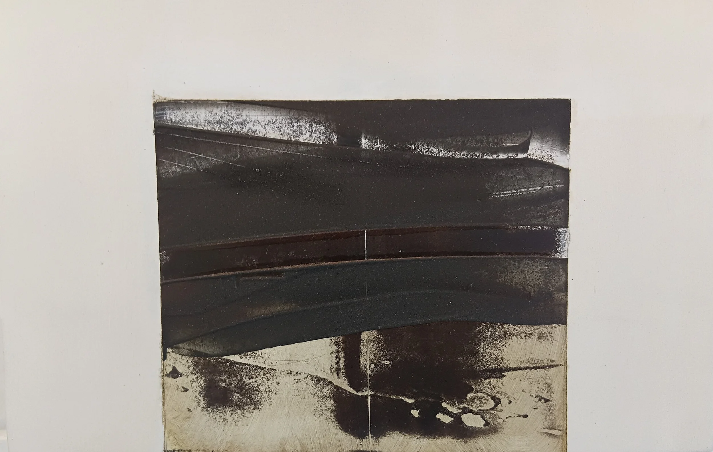 Close-up of a wall with a square cutout revealing a metal surface covered in black soot and ash with some white streaks.