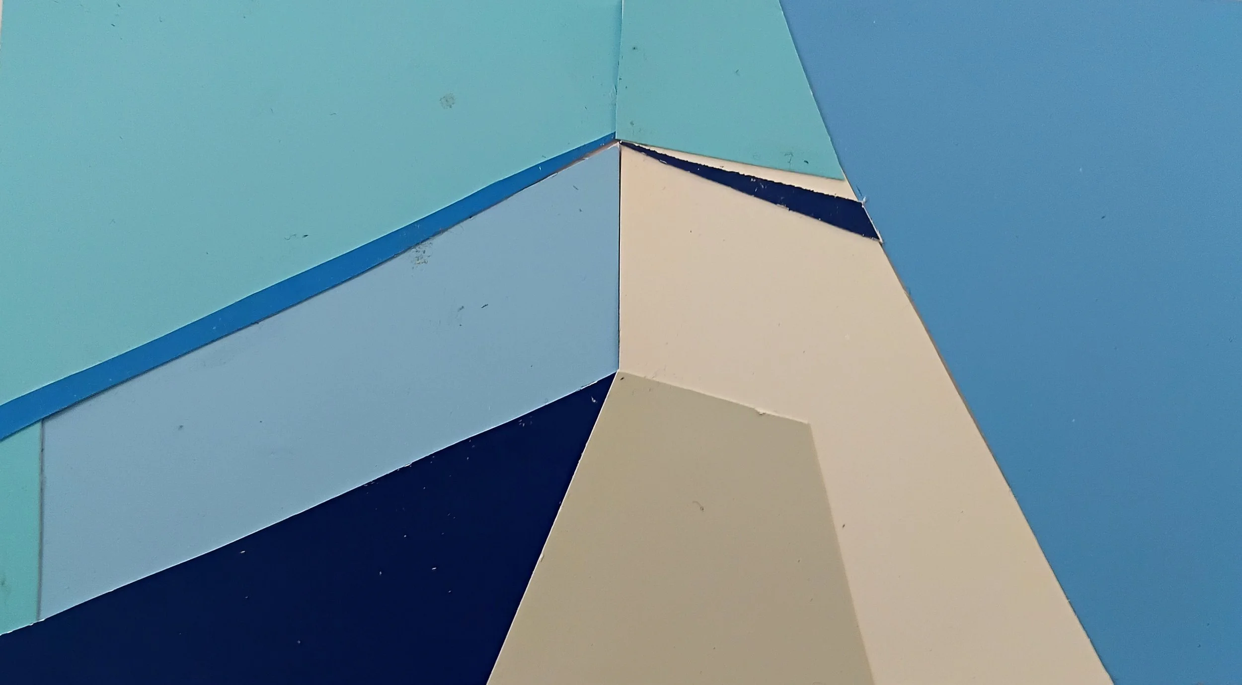 Close-up view of painted wooden panels in various shades of blue, teal, cream, and navy, arranged at different angles.