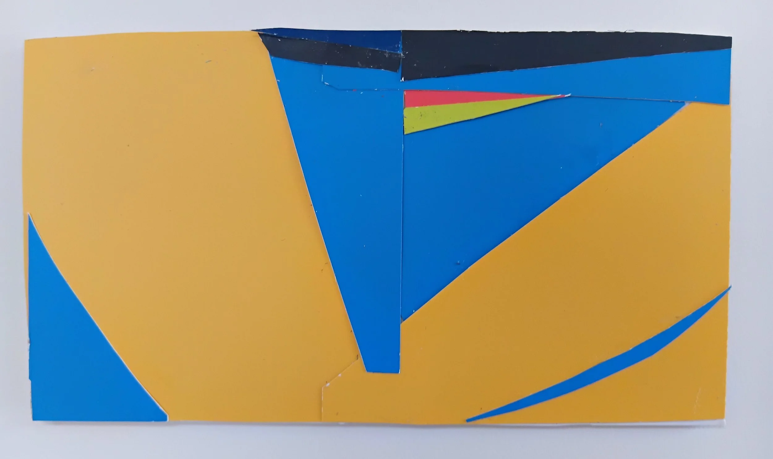Arrangement of colorful paper pieces in yellow, blue, black, red, and green, assembled in an abstract geometric pattern.