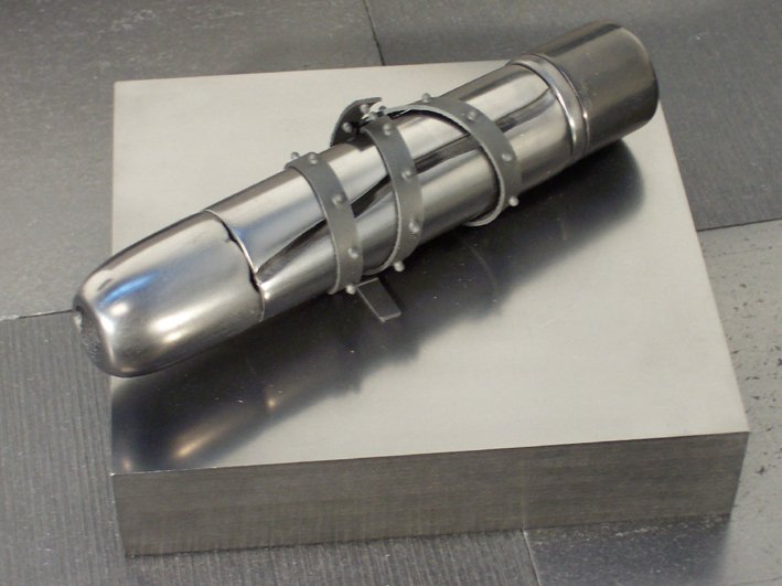 A metallic rifle-shaped sculpture displayed on a square pedestal.