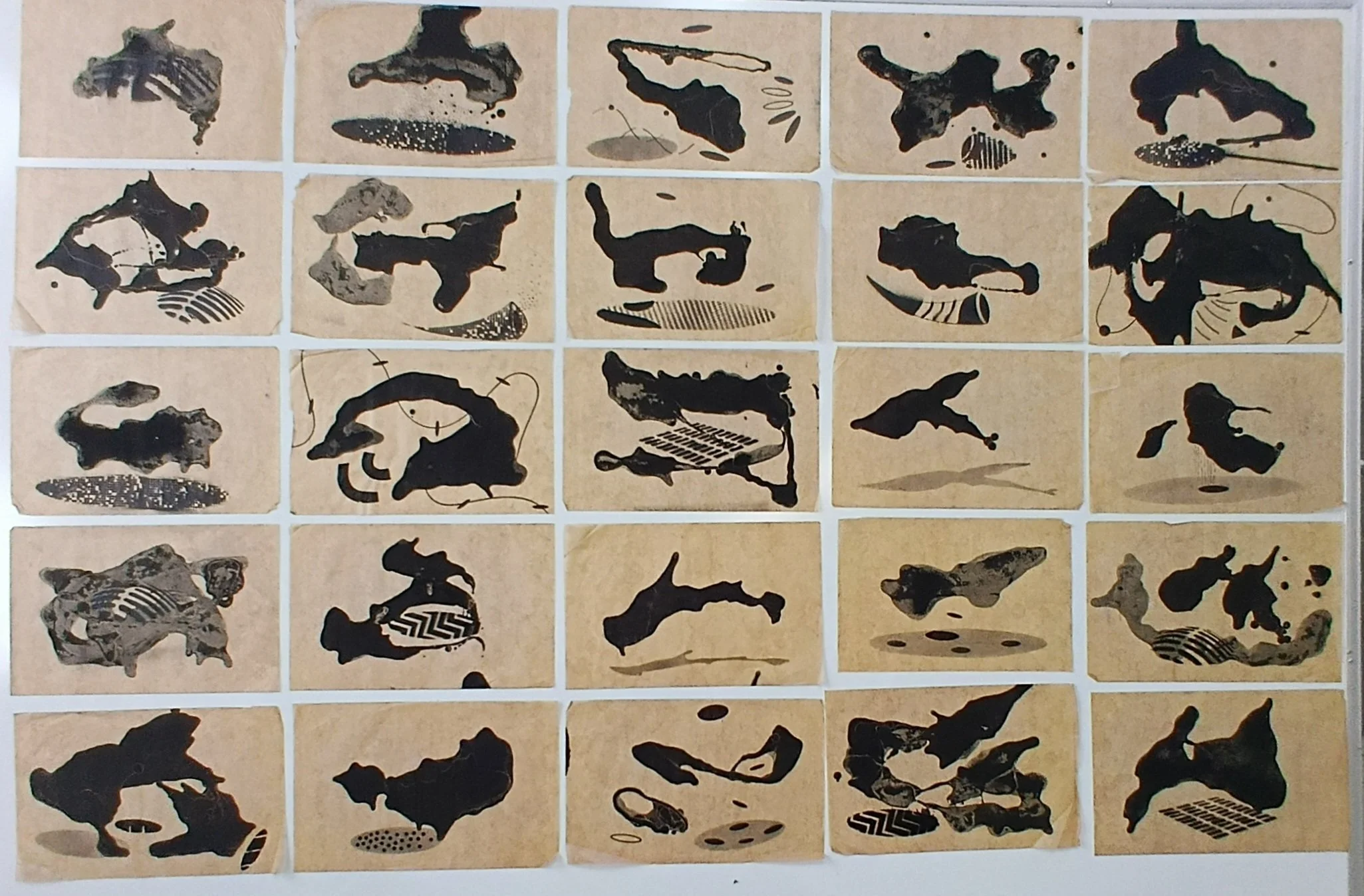 A collage of 20 abstract inkblot artworks on beige backgrounds arranged in a grid.