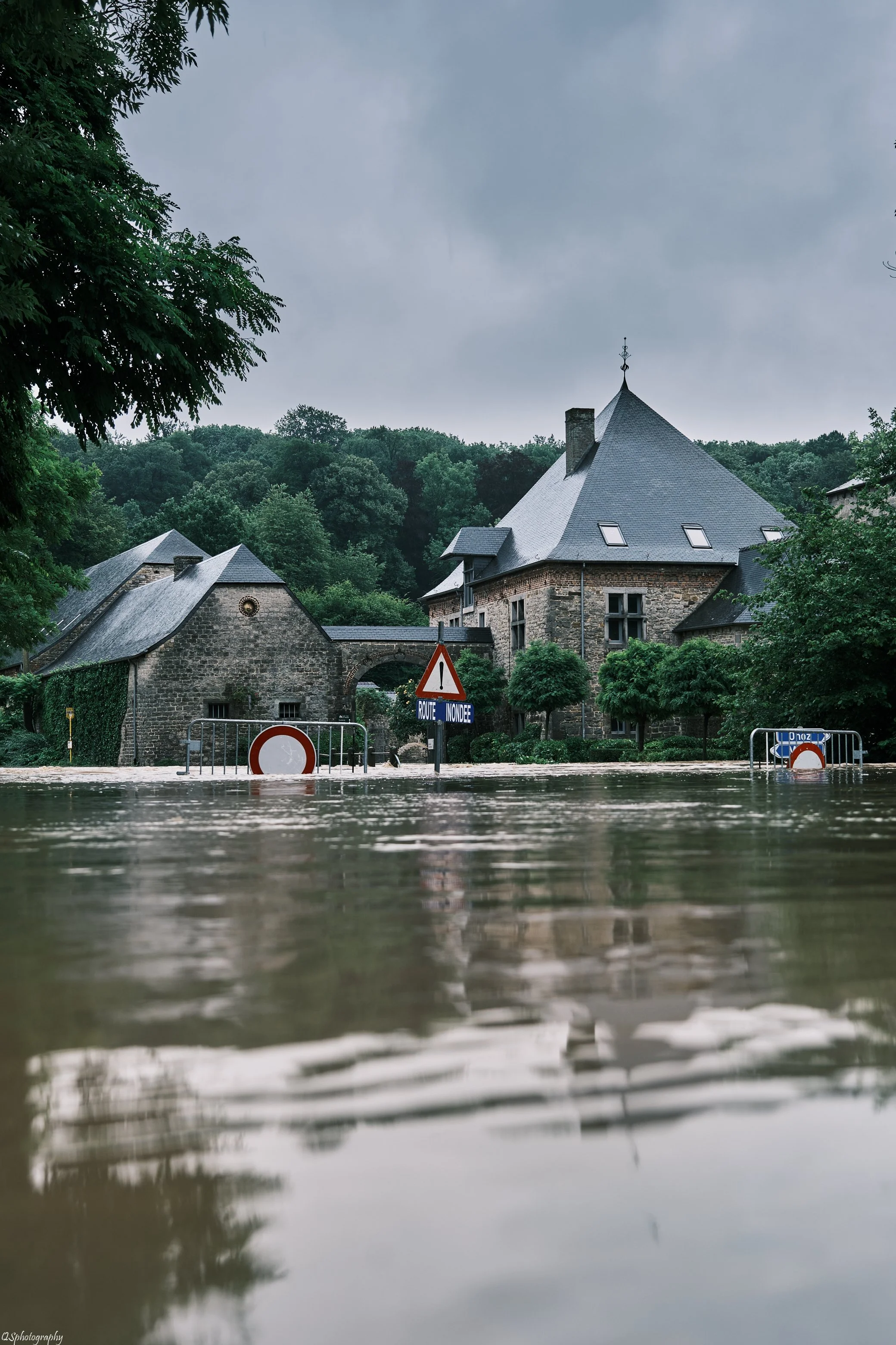 Une maison ancienne en pierre entourée d'arbres, inondée par des eaux de pluie,  | QSphotography | Namur
